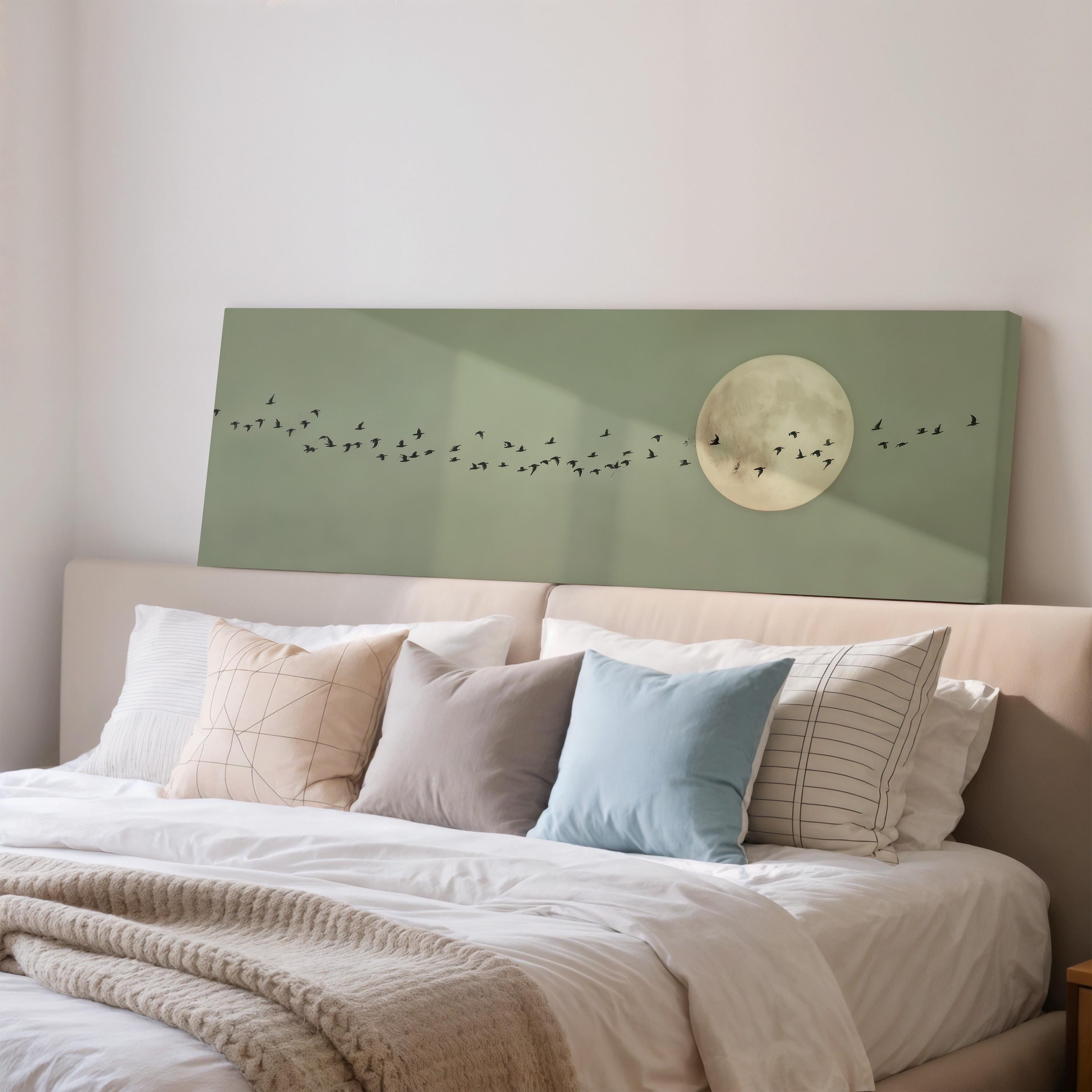 a cozy bedroom scene with a bed adorned with white sheets and a variety of colorful pillows. Above the bed, there is a large canvas featuring a flock of birds against a backdrop of a full moon.