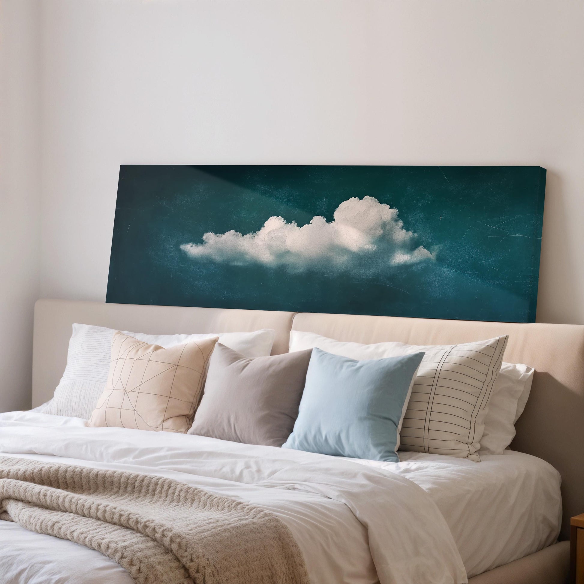a bedroom with a large bed covered in white sheets and pillows. Above the bed, there is a framed artwork depicting a cloud against a blue sky background.