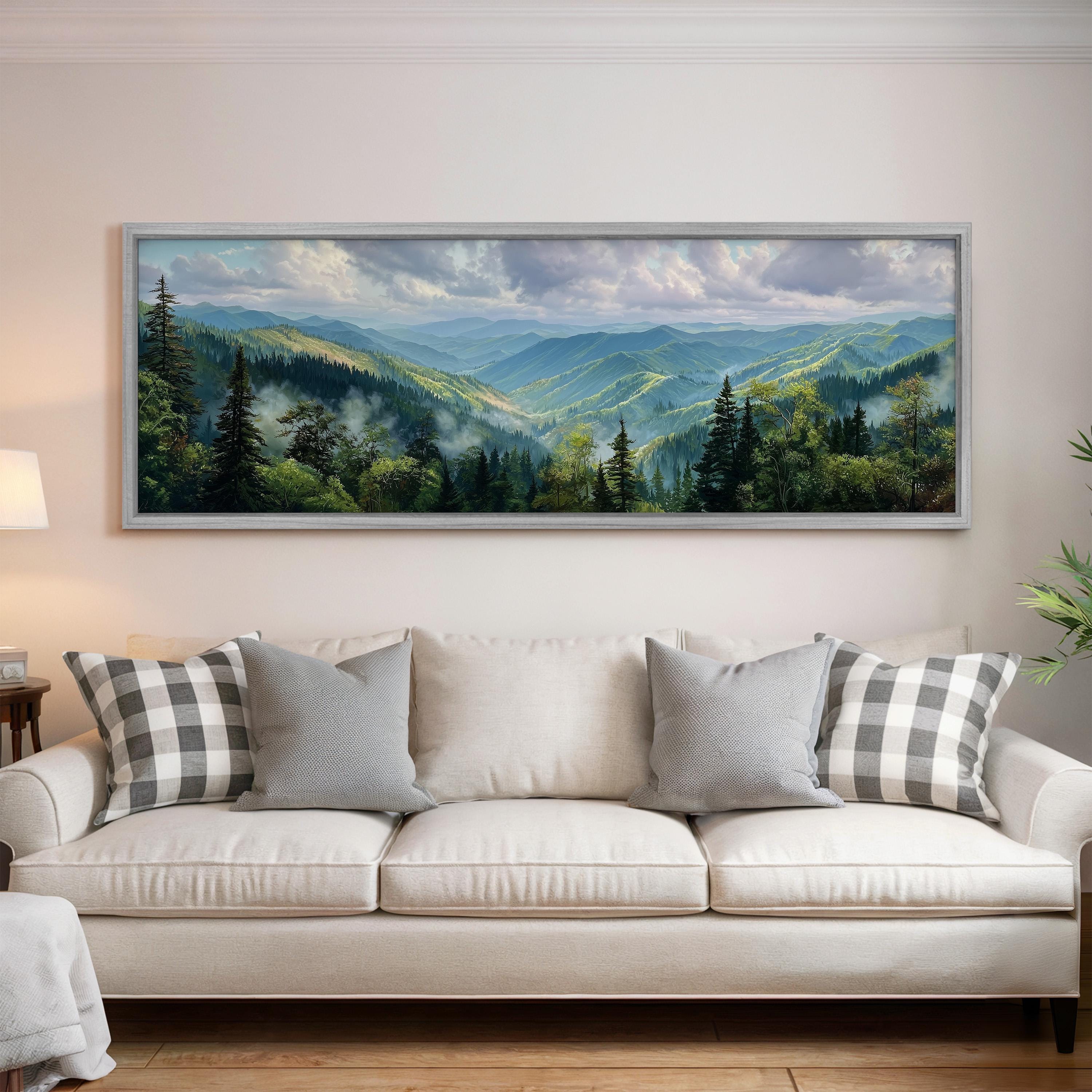 a large framed landscape painting hanging on a wall above a white sofa with gray and white patterned pillows.