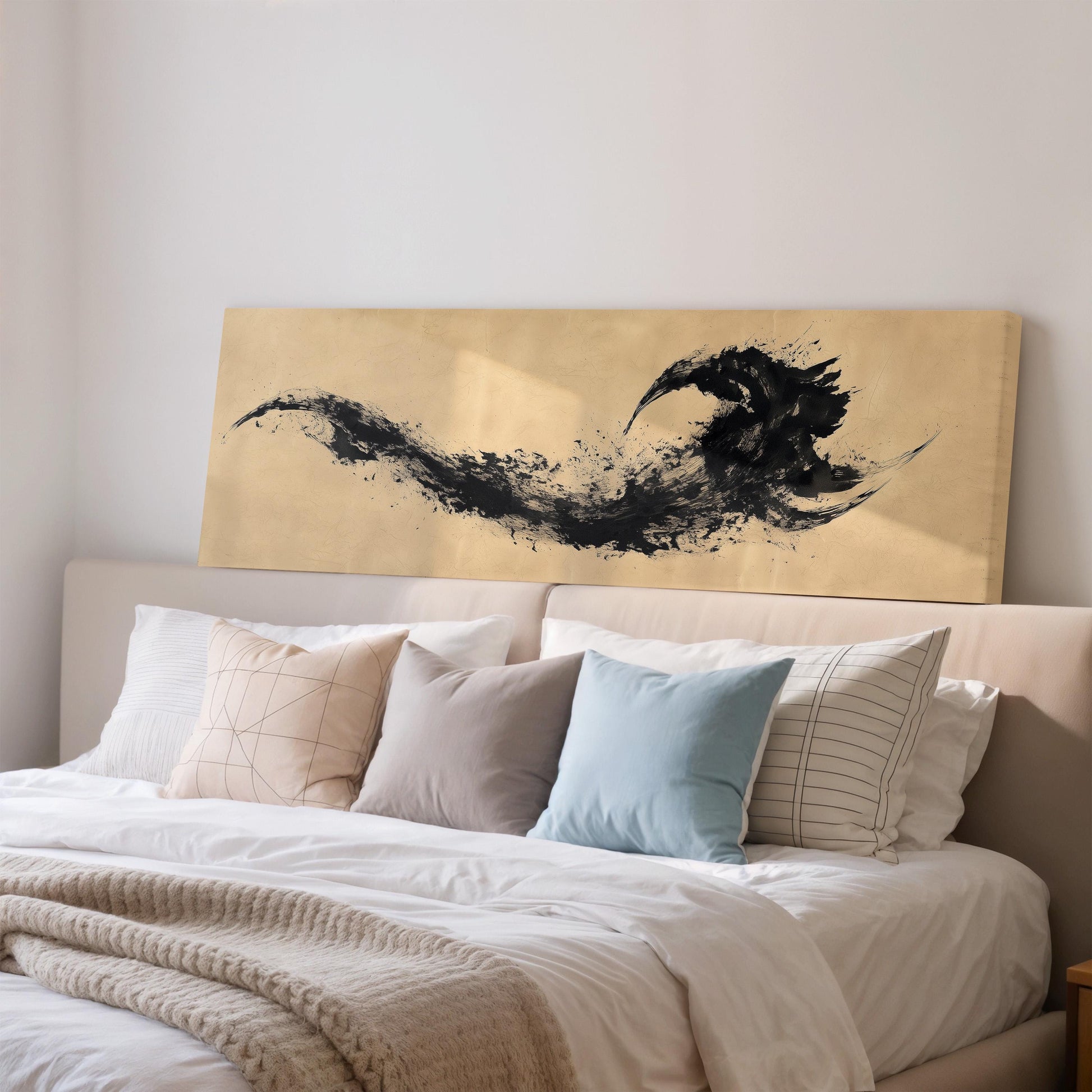 a large bed with a white comforter and various pillows, including a blue pillow and a striped pillow. Above the bed, there is a large painting or artwork depicting a black bird or creature.