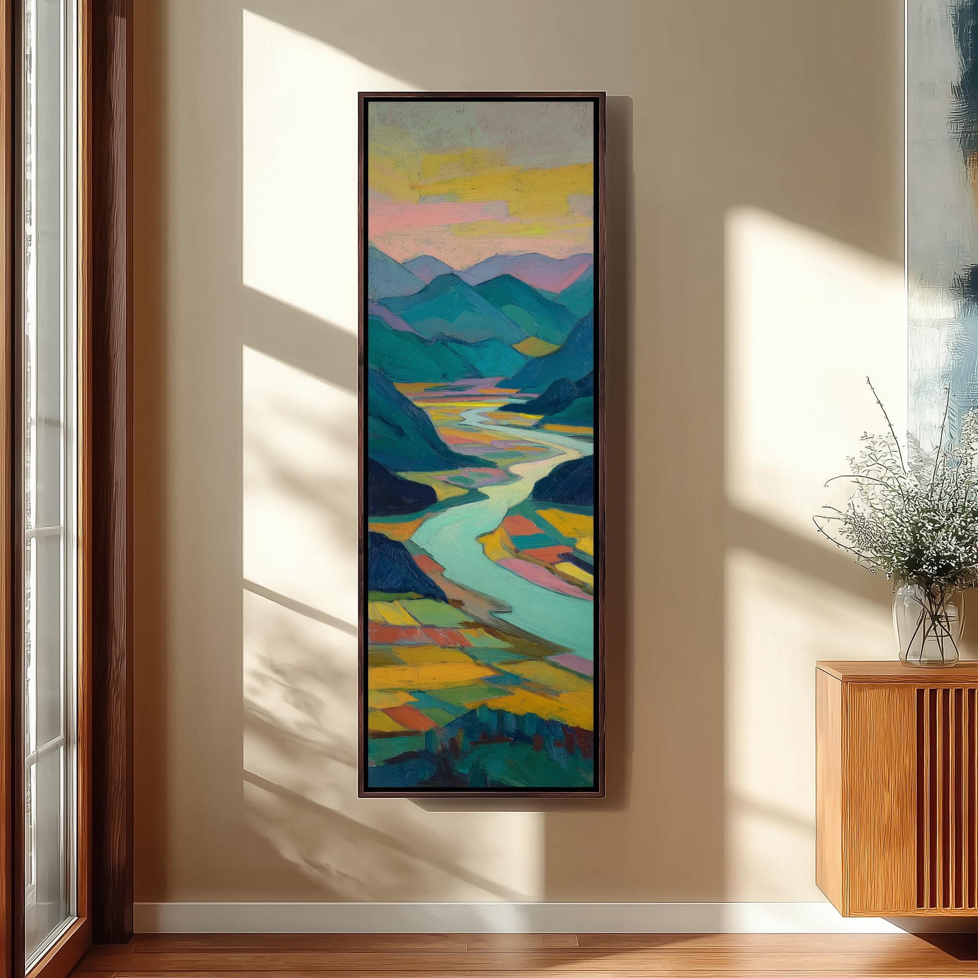 a large, colorful painting of a landscape with mountains, a river, and a sky with clouds, hanging on a wall in a room with a wooden cabinet and a vase of flowers.