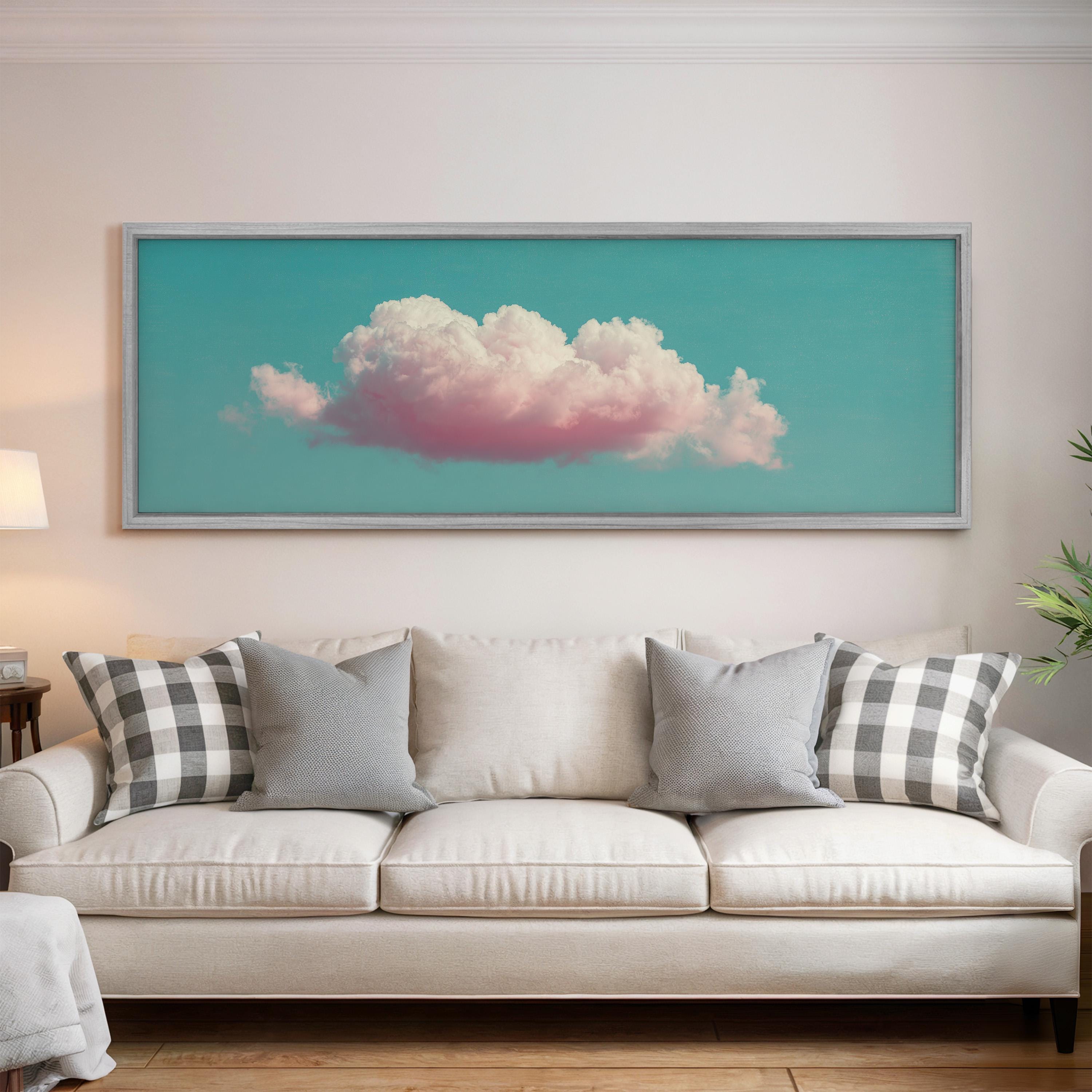a large framed picture of a cloud hanging on a wall above a white couch with gray and black plaid throw pillows.