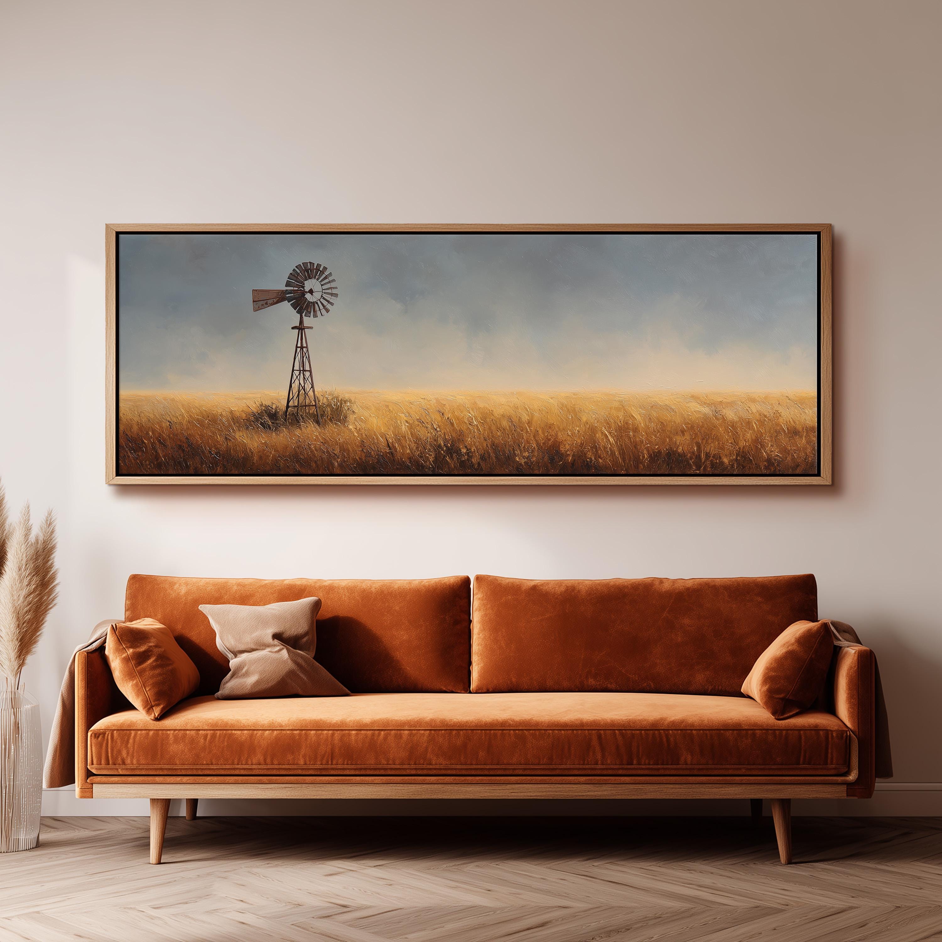 a large painting of a windmill in a field, hanging on a wall above a brown sofa.