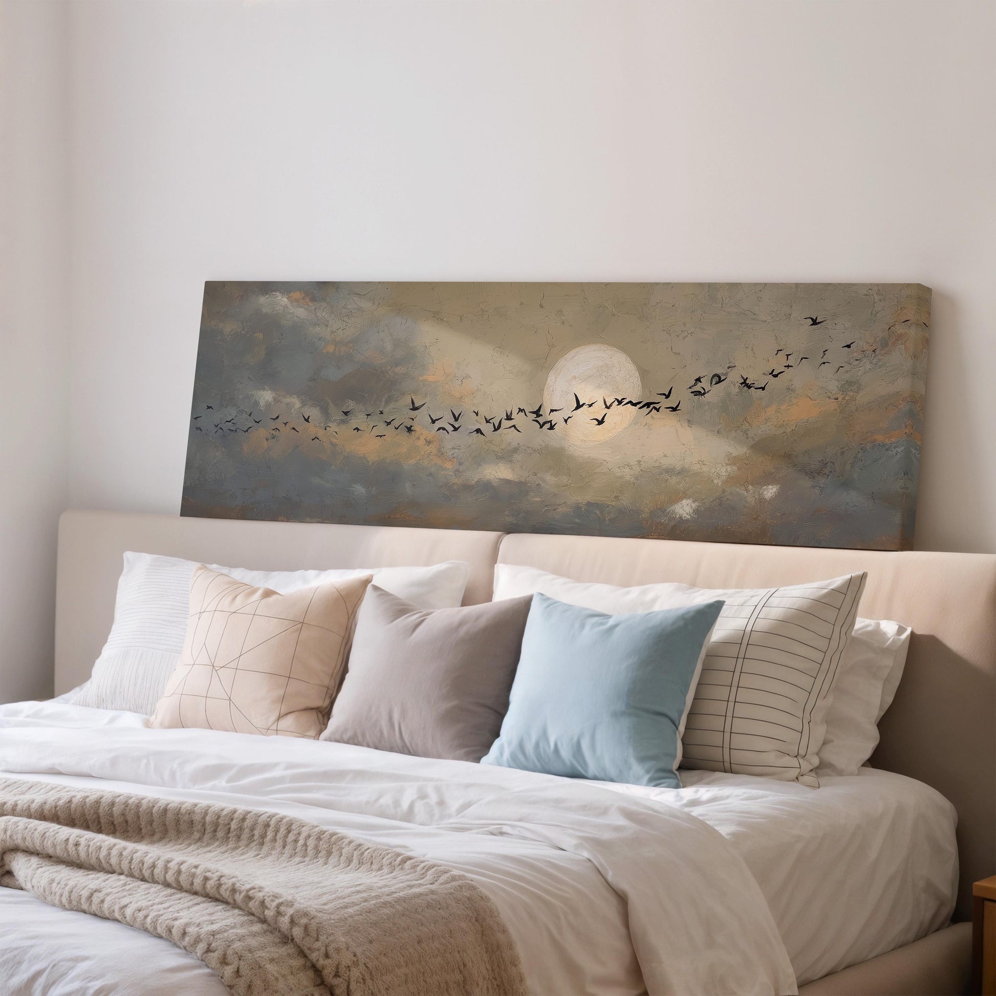 a serene bedroom scene with a large bed adorned with white linens and a blue throw pillow. Above the bed, a painting of a flock of birds flying across a cloudy sky is displayed, creating a peaceful and tranquil atmosphere.
