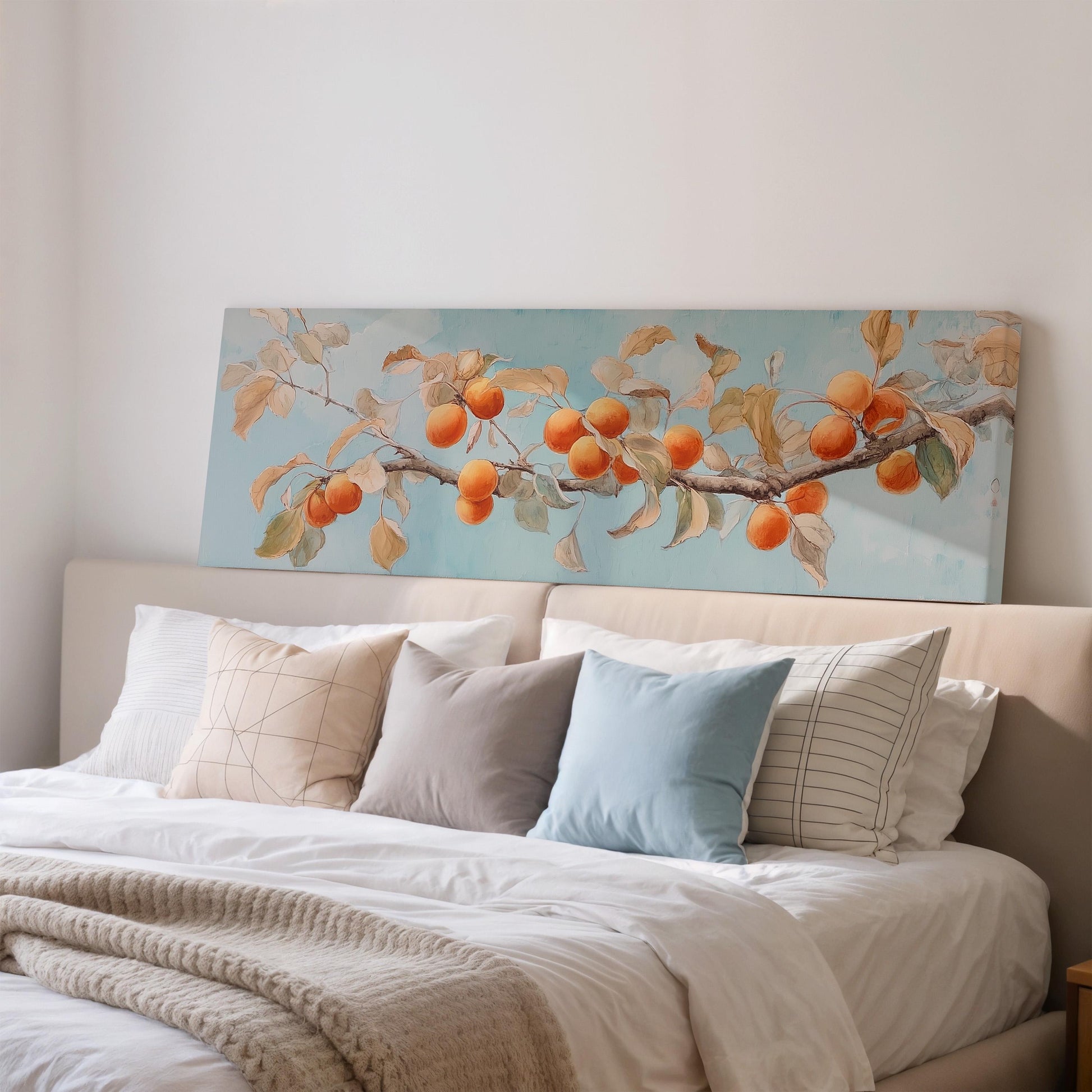 a large painting of a tree branch with orange fruits hanging from it, displayed on a wall above a bed with white pillows and a gray blanket.