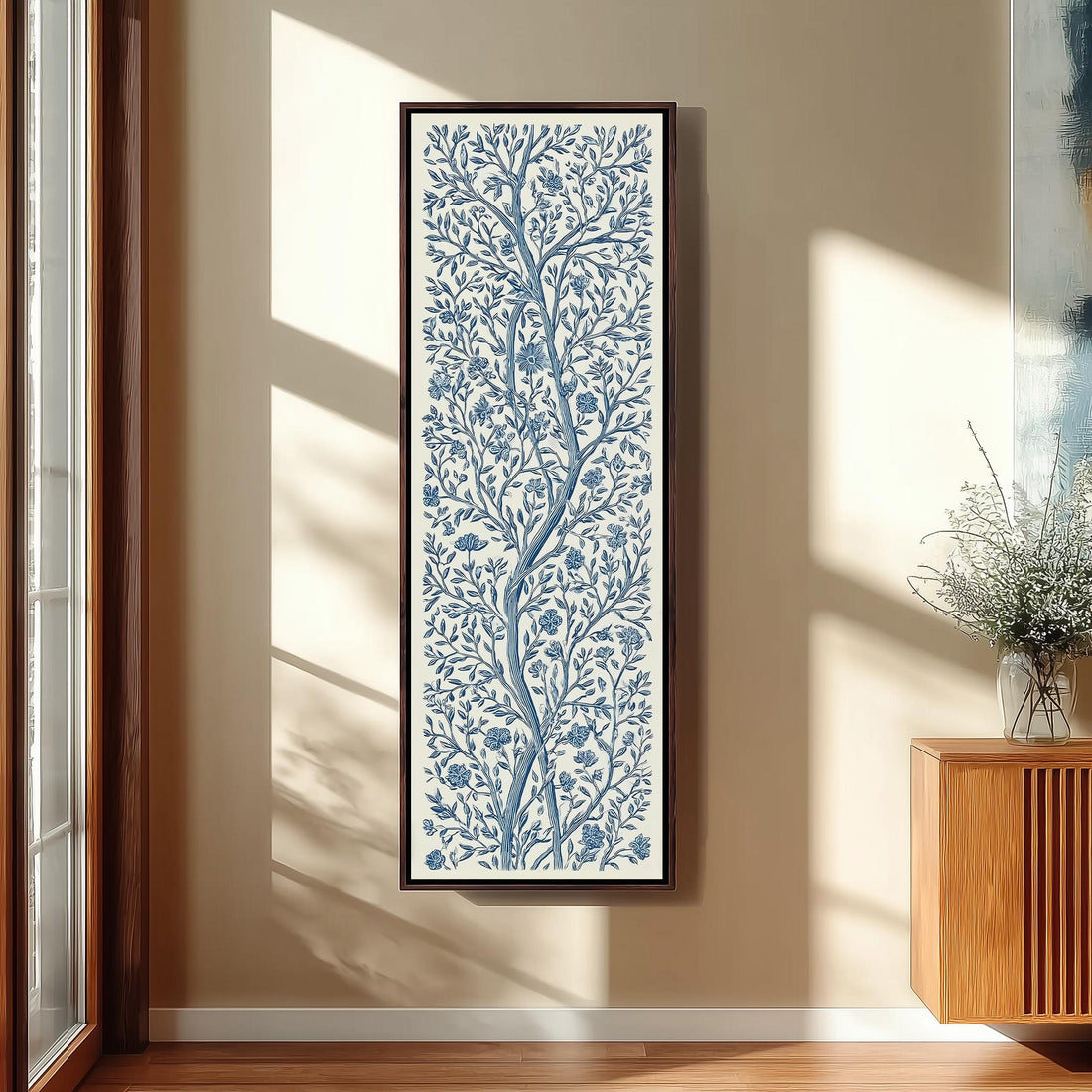 a living room with a large blue and white floral print hanging on the wall, a wooden chair, a small table, and a window with a plant on the sill.