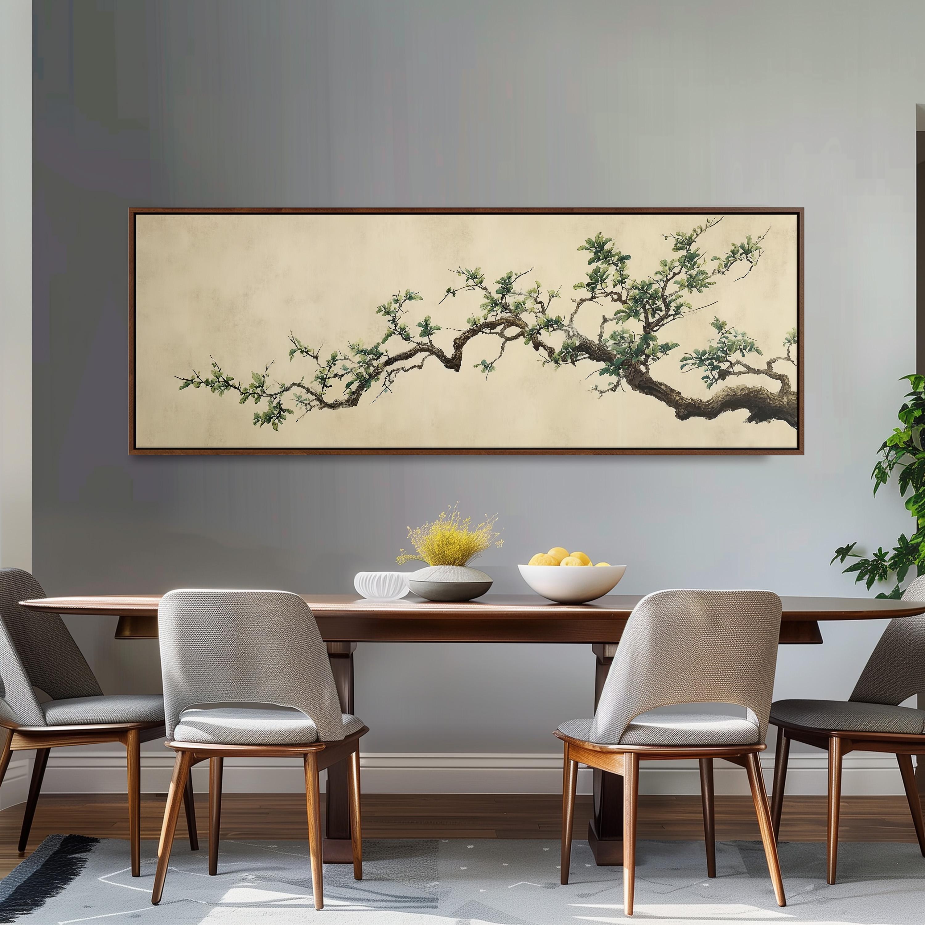 a dining room with a wooden table and four chairs, a large framed painting of a tree branch hanging above the table, and a bowl of fruit on the table.