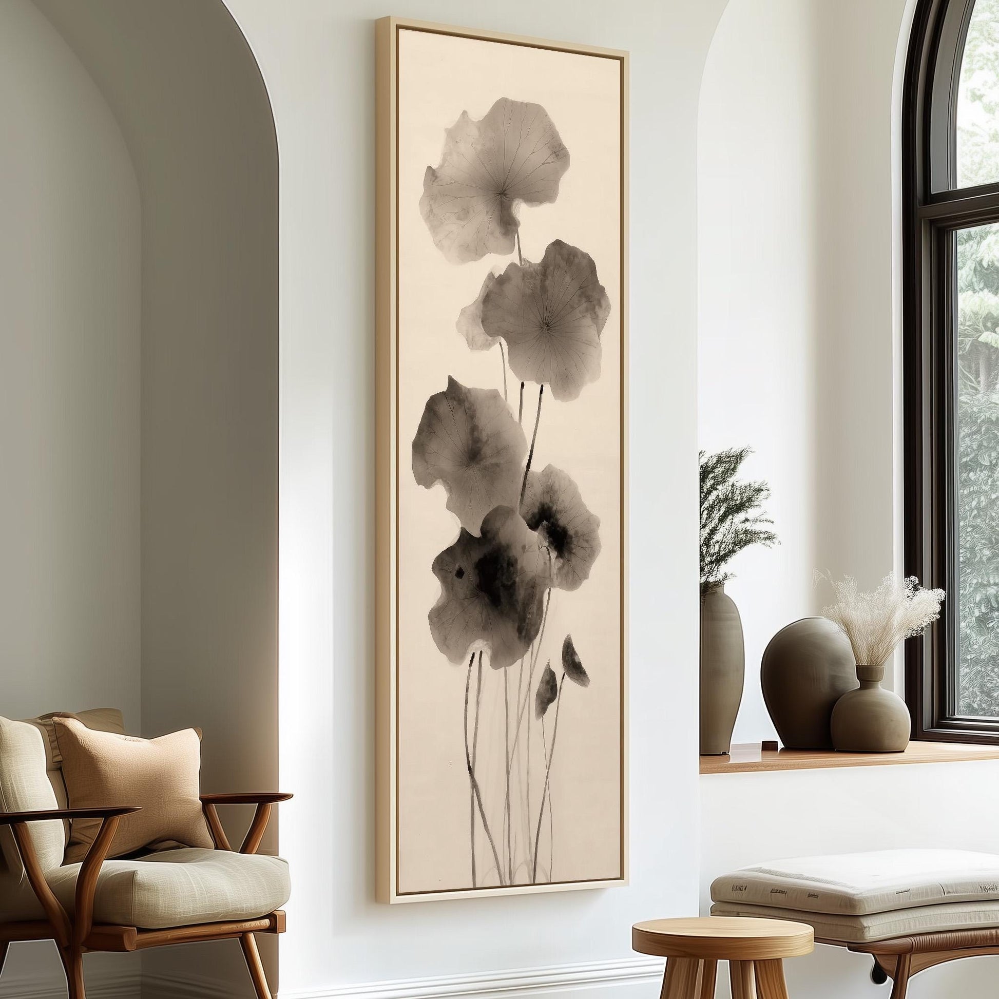 a minimalist living room with a large framed artwork of black and white flowers hanging on the wall. The room is furnished with a chair, a table, and a window with a plant on the sill.
