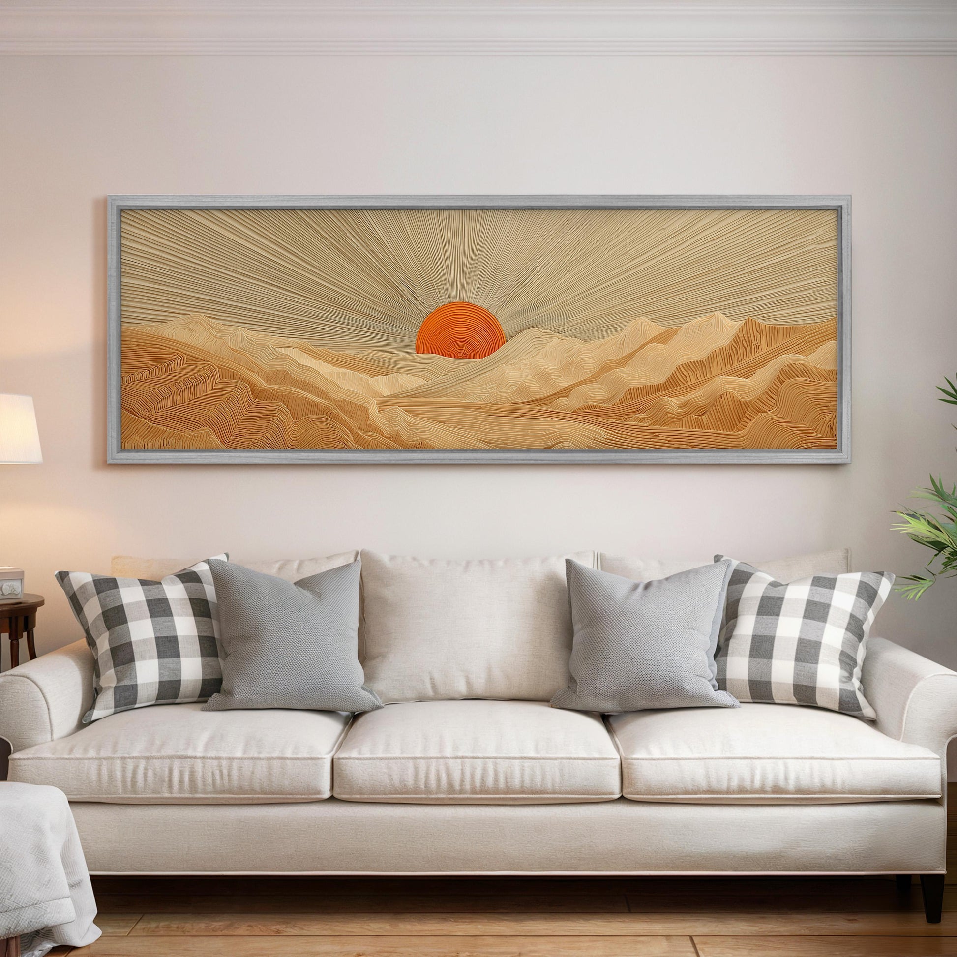 a large, framed painting of a desert landscape with a sun in the background, hanging on a wall above a white couch with gray and white plaid throw pillows.