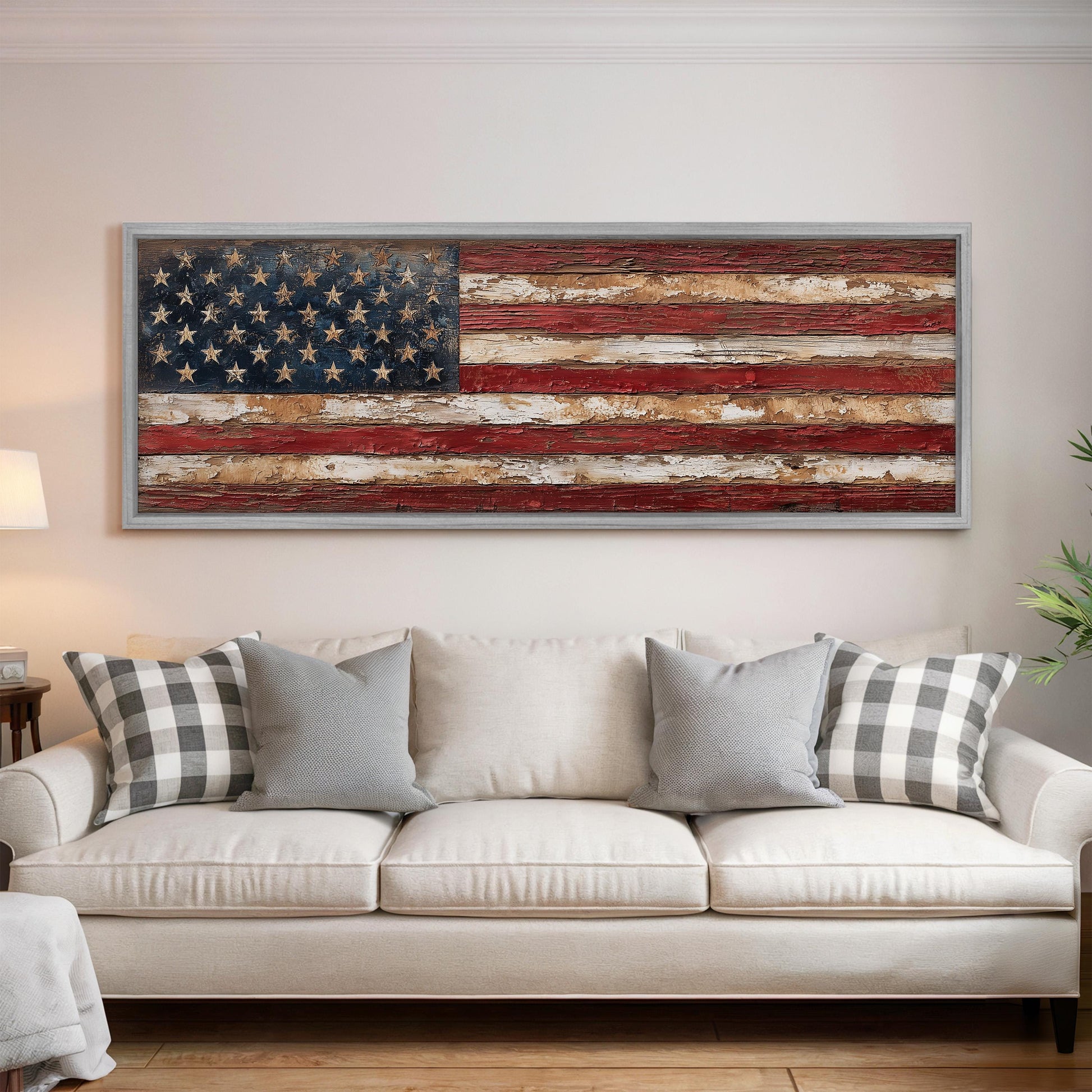 a large American flag displayed on the wall above a white couch with gray and white plaid throw pillows.