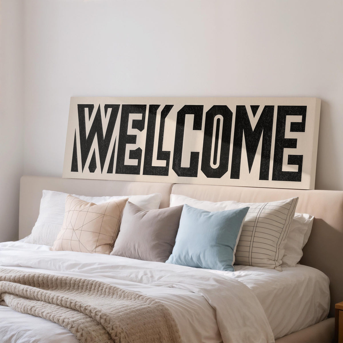 Bold welcome block letters wide panoramic canvas print above a bed in a bedroom