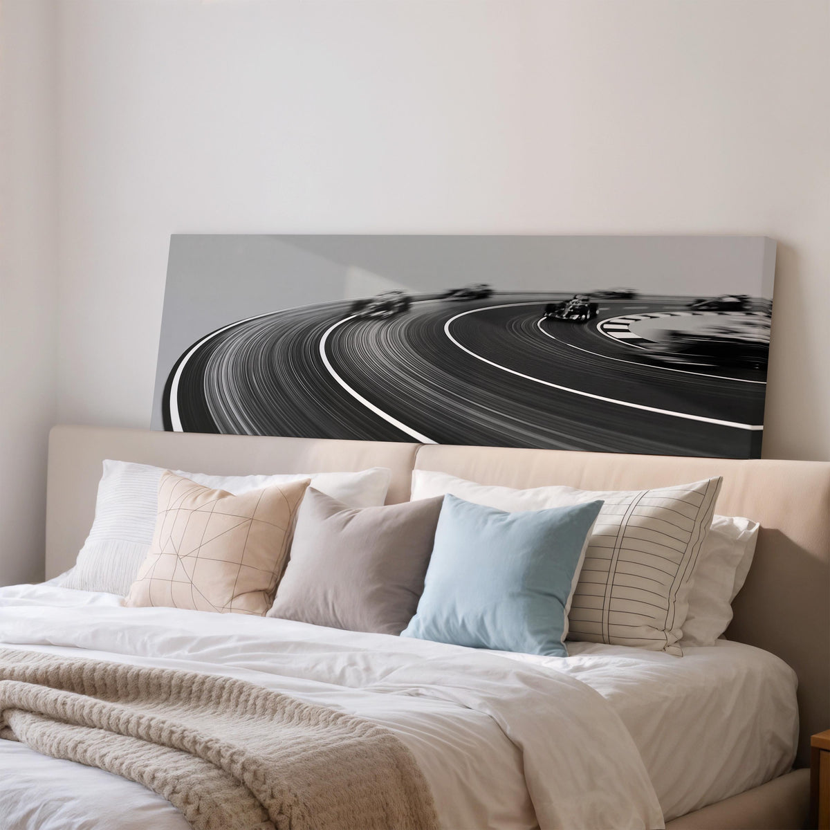 Race cars sweeping around a curve in black and white wide panoramic canvas print above a bed in a bedroom
