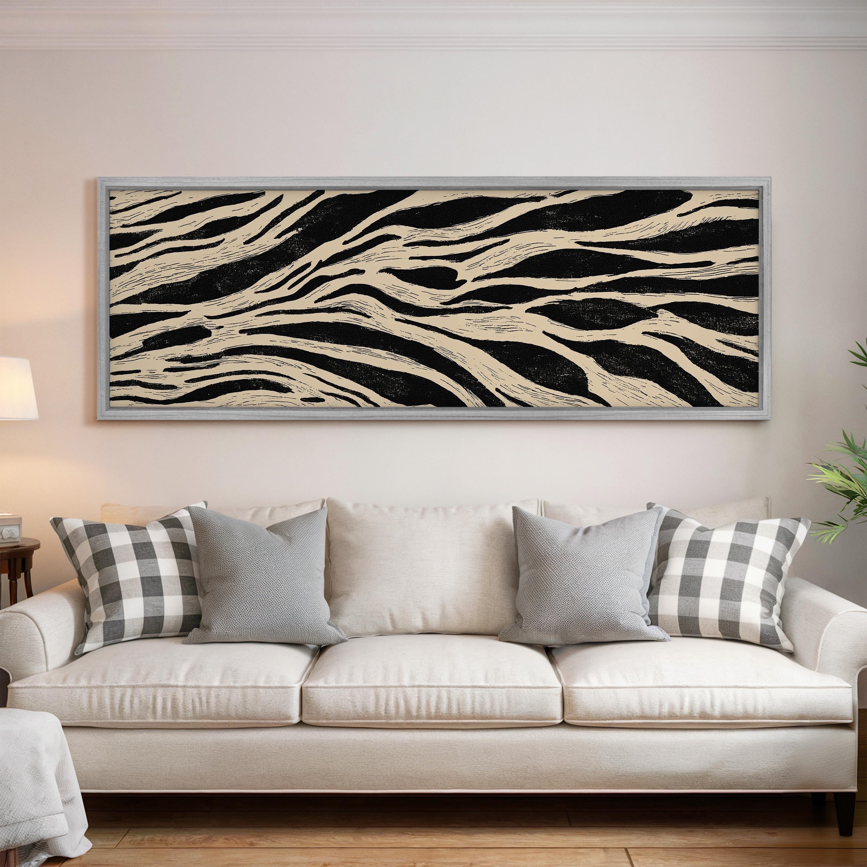 a living room with a white sofa adorned with gray and white plaid throw pillows. Above the sofa, there is a large black and white abstract painting hanging on the wall.