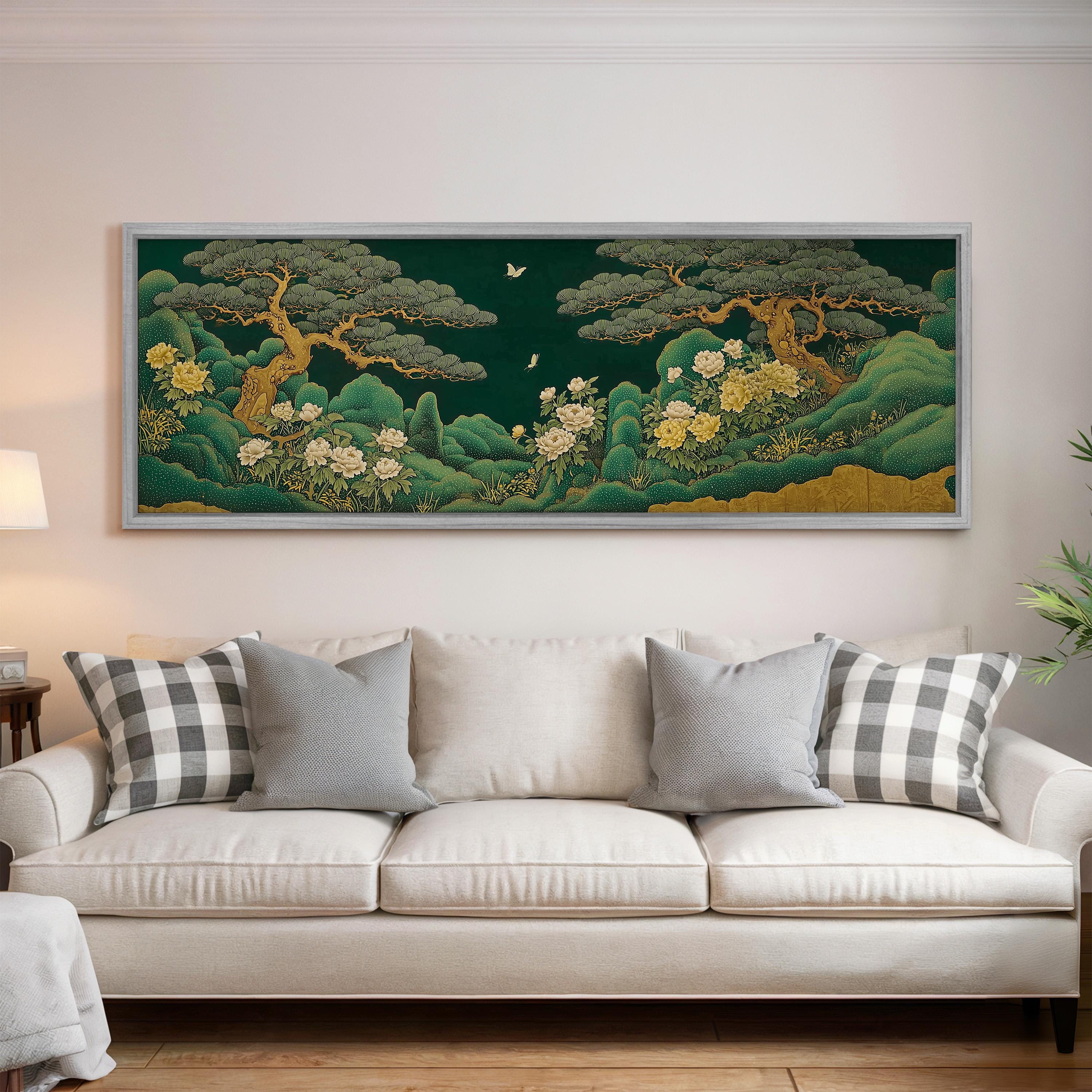 a large, framed painting of a serene landscape with trees, flowers, and a night sky, hanging on a wall above a white couch with decorative pillows.