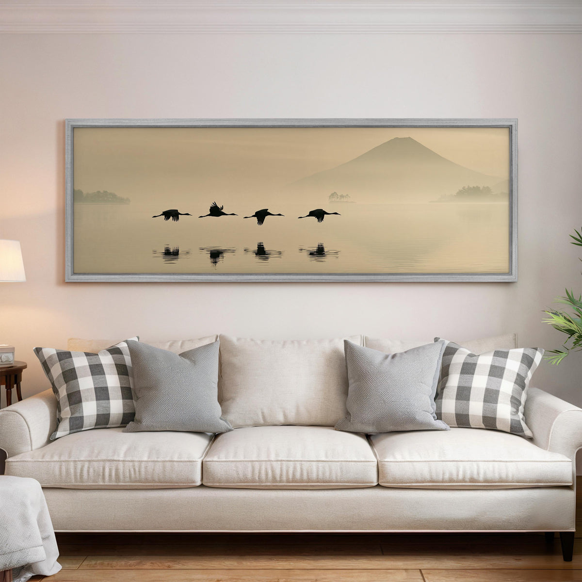 Birds flying low over a lake below Mount Fuji panoramic canvas print above a white sofa in a bright living room
