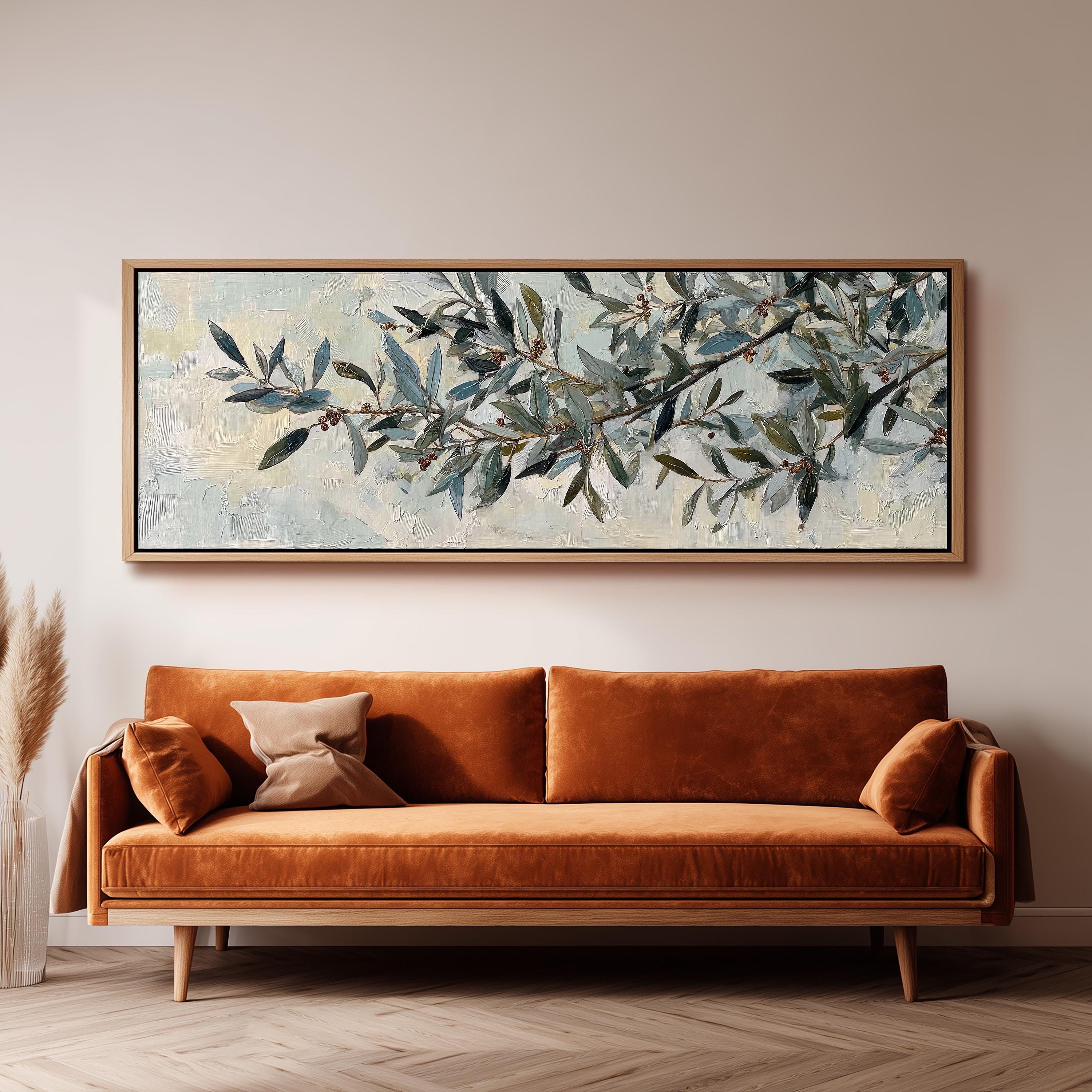 a large painting of a tree branch with green leaves and brown branches hanging on a wall above a brown sofa with orange cushions.