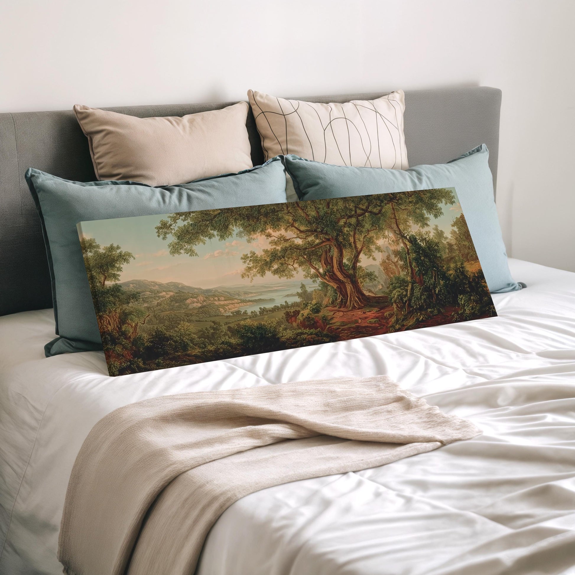 a large landscape painting displayed on a bed, surrounded by pillows.