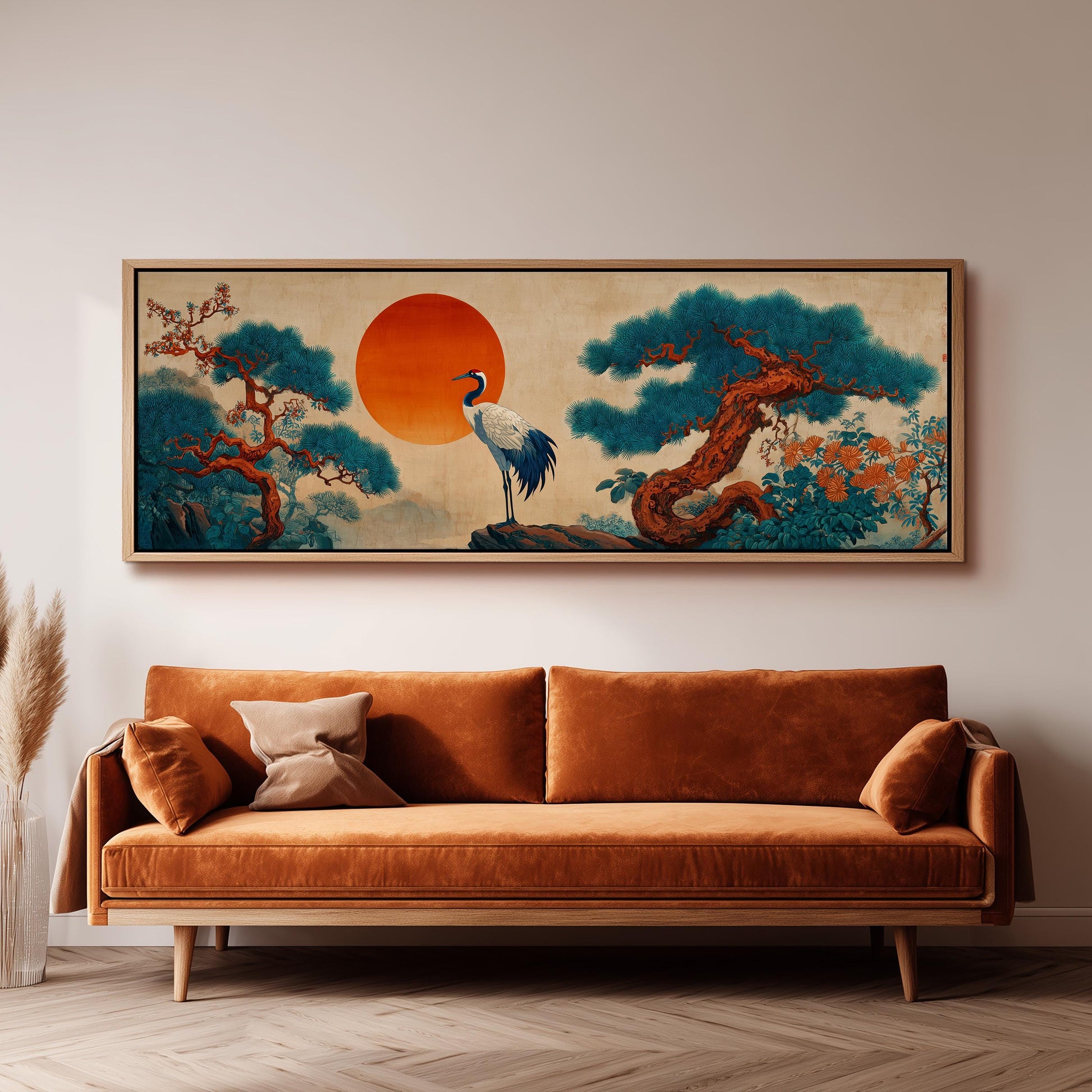 a large, framed painting of a crane standing on a rock, surrounded by a landscape with trees and a large orange sun in the sky. The painting is hanging on a wall above a brown sofa.