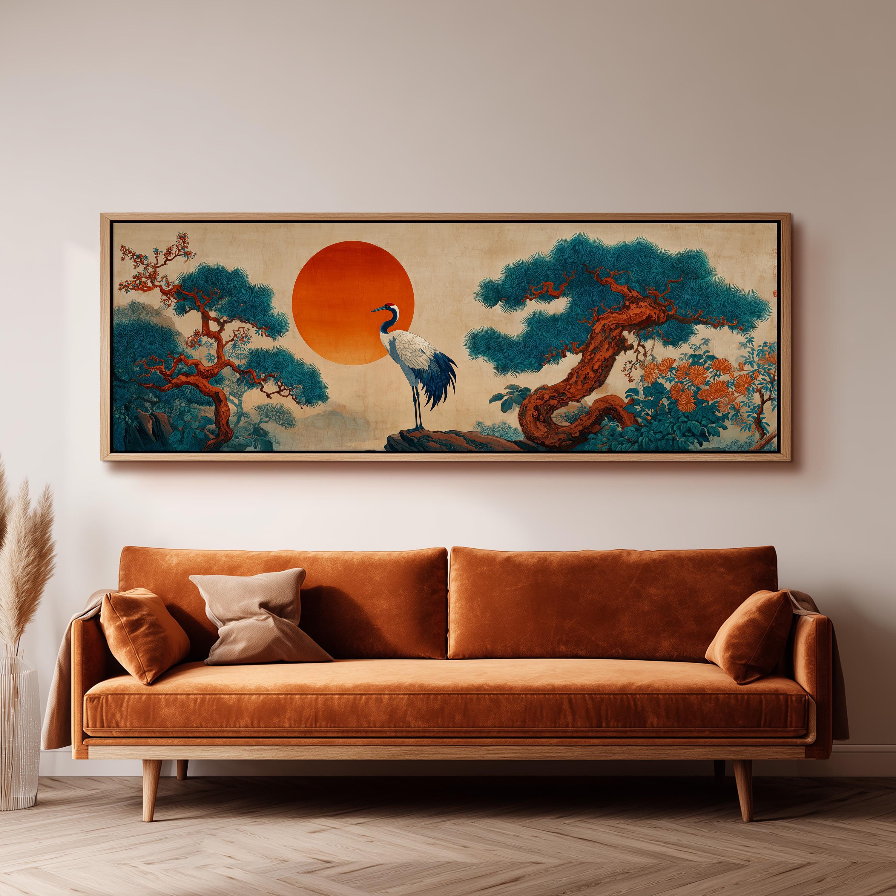 a large, framed painting of a crane standing on a rock, surrounded by a landscape with trees and a large orange sun in the sky. The painting is hanging on a wall above a brown sofa.
