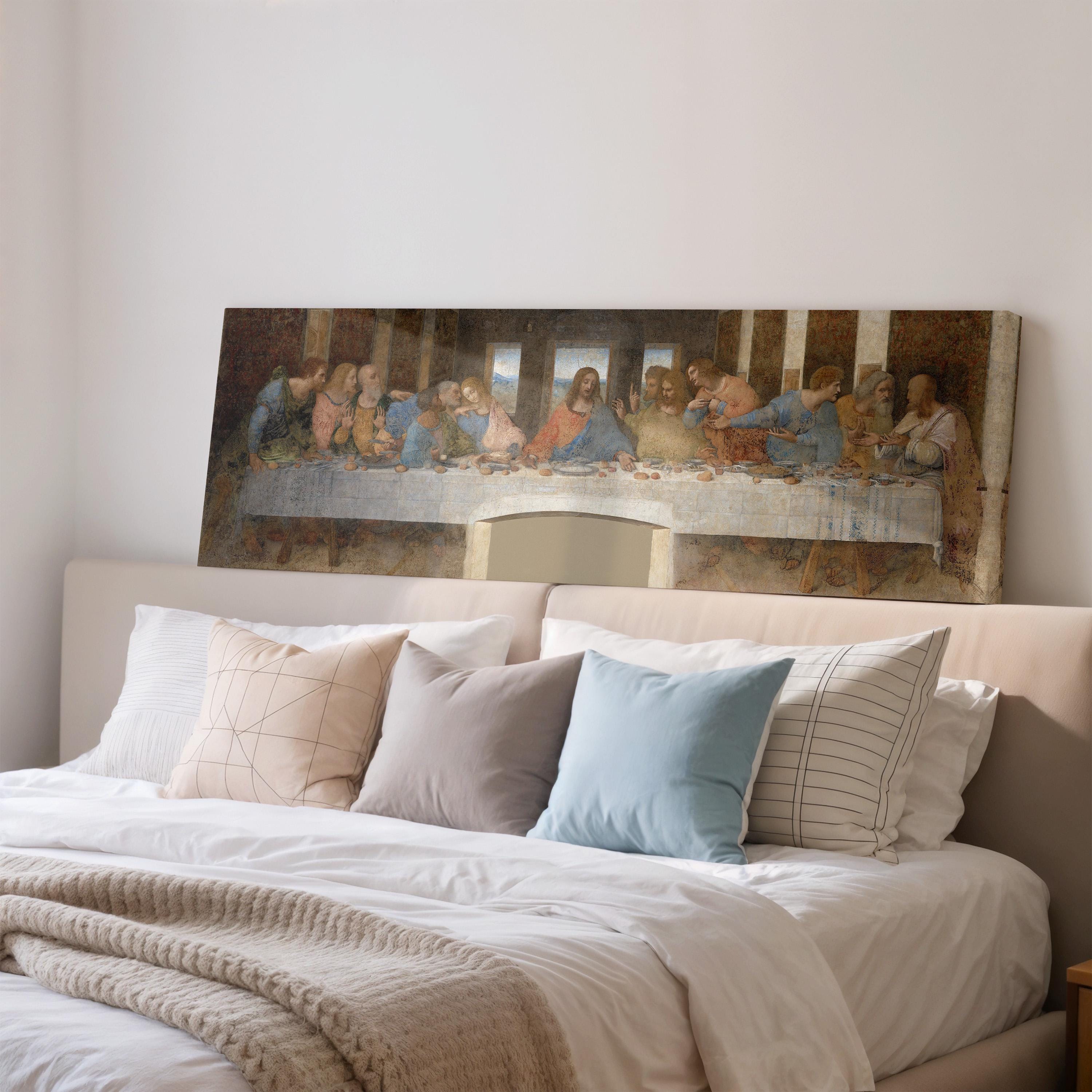 a large painting of the Last Supper hanging on a wall above a bed with pillows.
