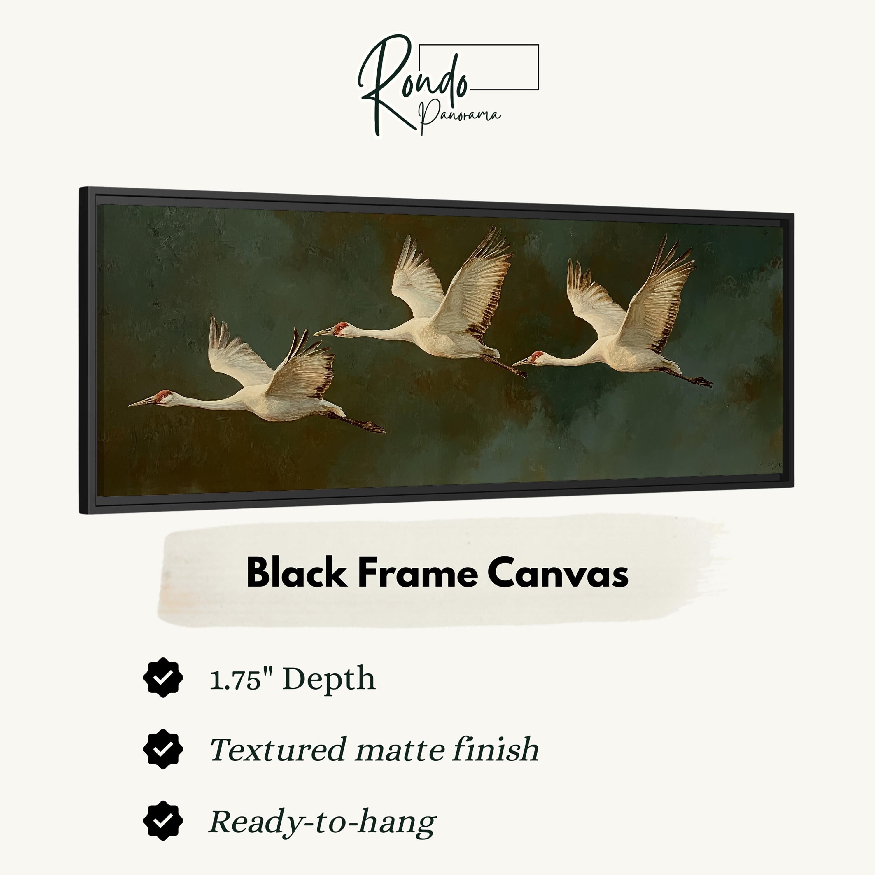 a black frame canvas with a painting of three swans in flight.