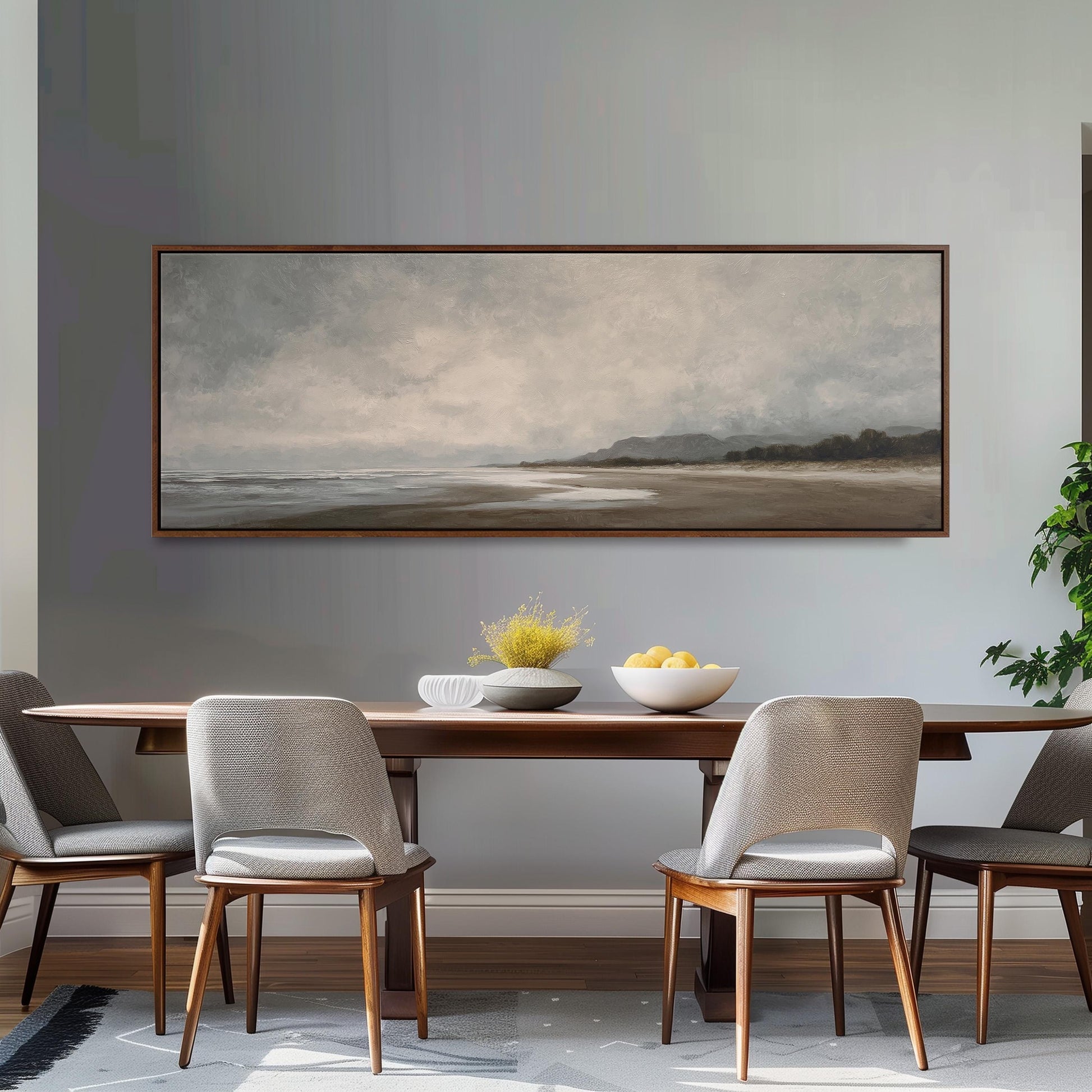a dining room with a large painting of a beach scene hanging on the wall above a wooden dining table with four chairs. The table is set with a bowl of fruit and a vase of flowers, creating a cozy and inviting atmosphere.