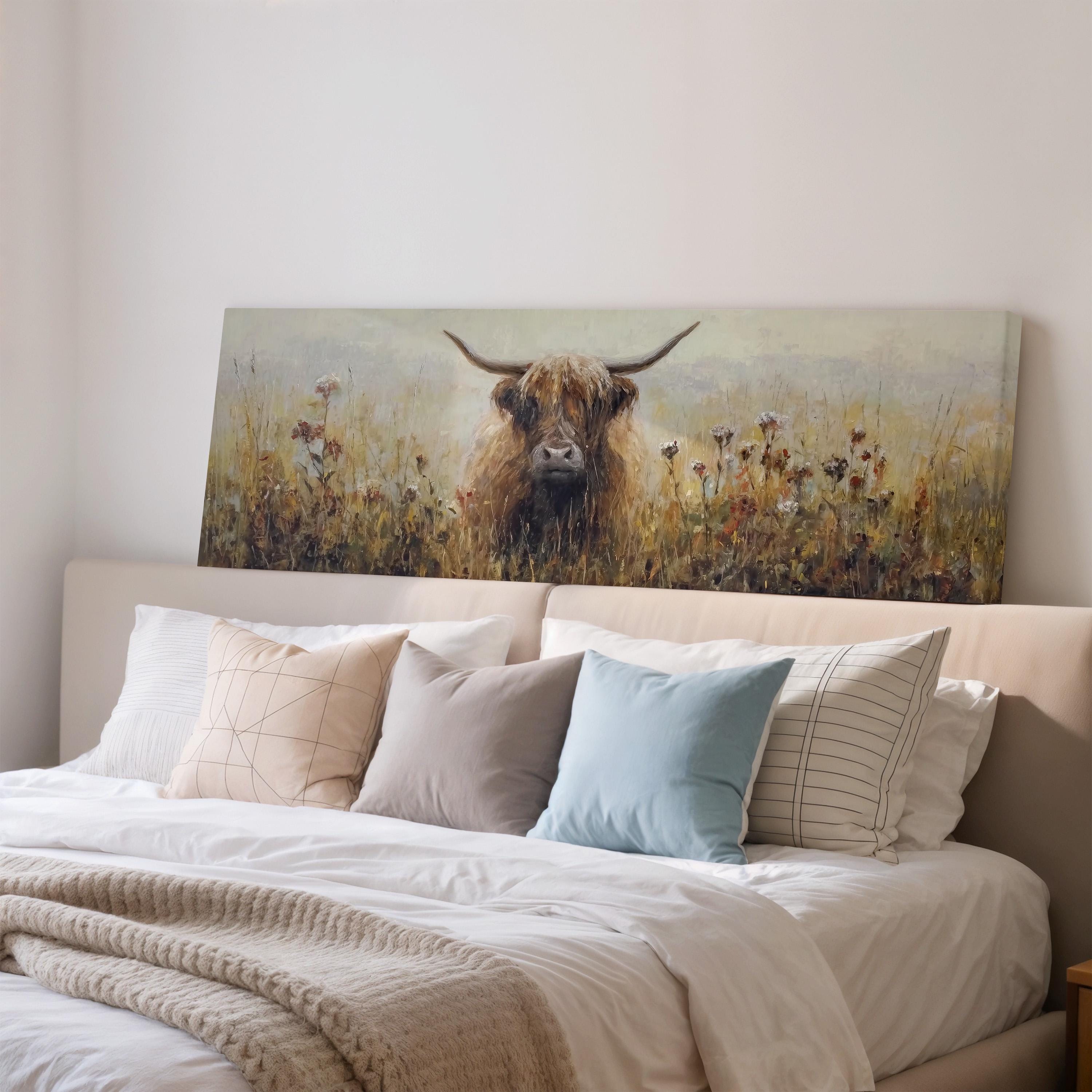 a large painting of a cow with horns, displayed on a wall above a bed with pillows and blankets.
