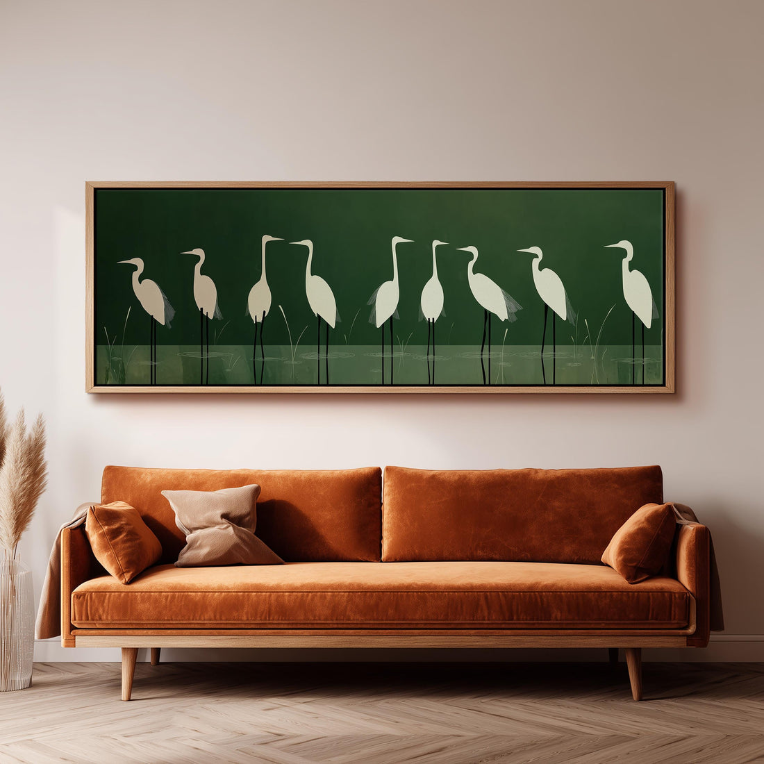 a large framed artwork of white birds standing on a green background, hanging above a brown sofa in a living room setting.