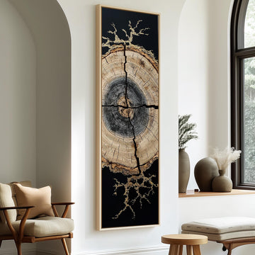 a large, abstract painting of a tree trunk with a black background and gold accents, hanging on a white wall. The painting is framed in black and is positioned between two chairs, one on each side. The room also includes a window, a small table, and some decorative elements such as vases and a potted plant.