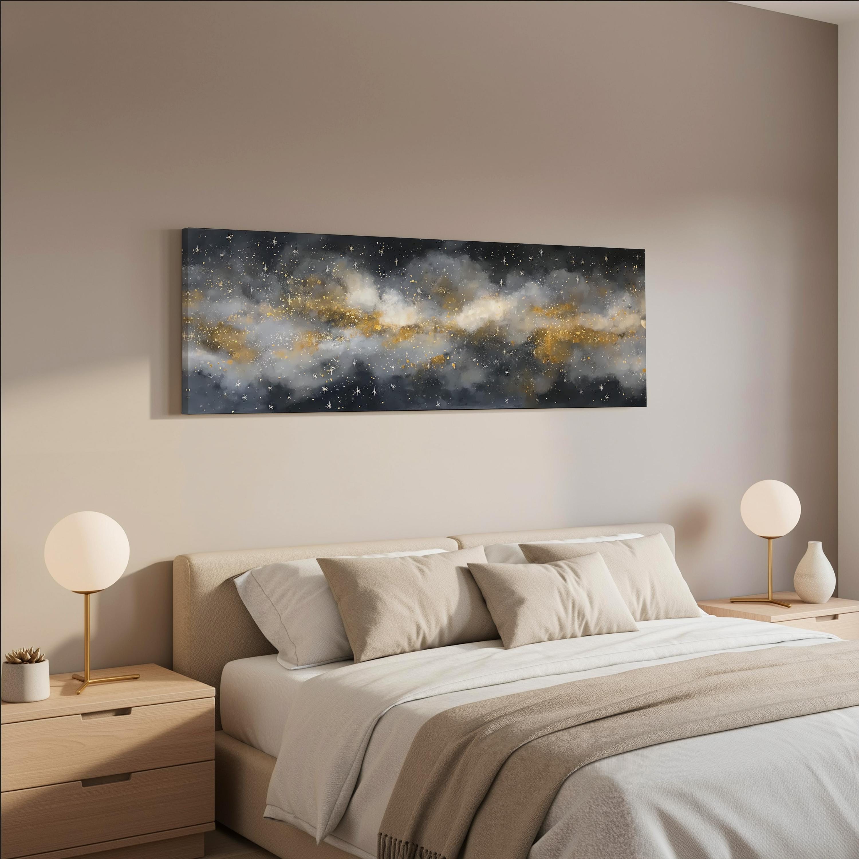 a serene and modern bedroom with a large bed adorned with white linens and beige throw pillows. Above the bed, a large black and white painting of a starry night sky is displayed on the wall, creating a striking contrast with the warm tones of the room. The bed is flanked by two white lamps, adding to the overall minimalist and elegant aesthetic of the space.