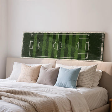 a bedroom with a bed and a large canvas print of a soccer field on the wall above it.