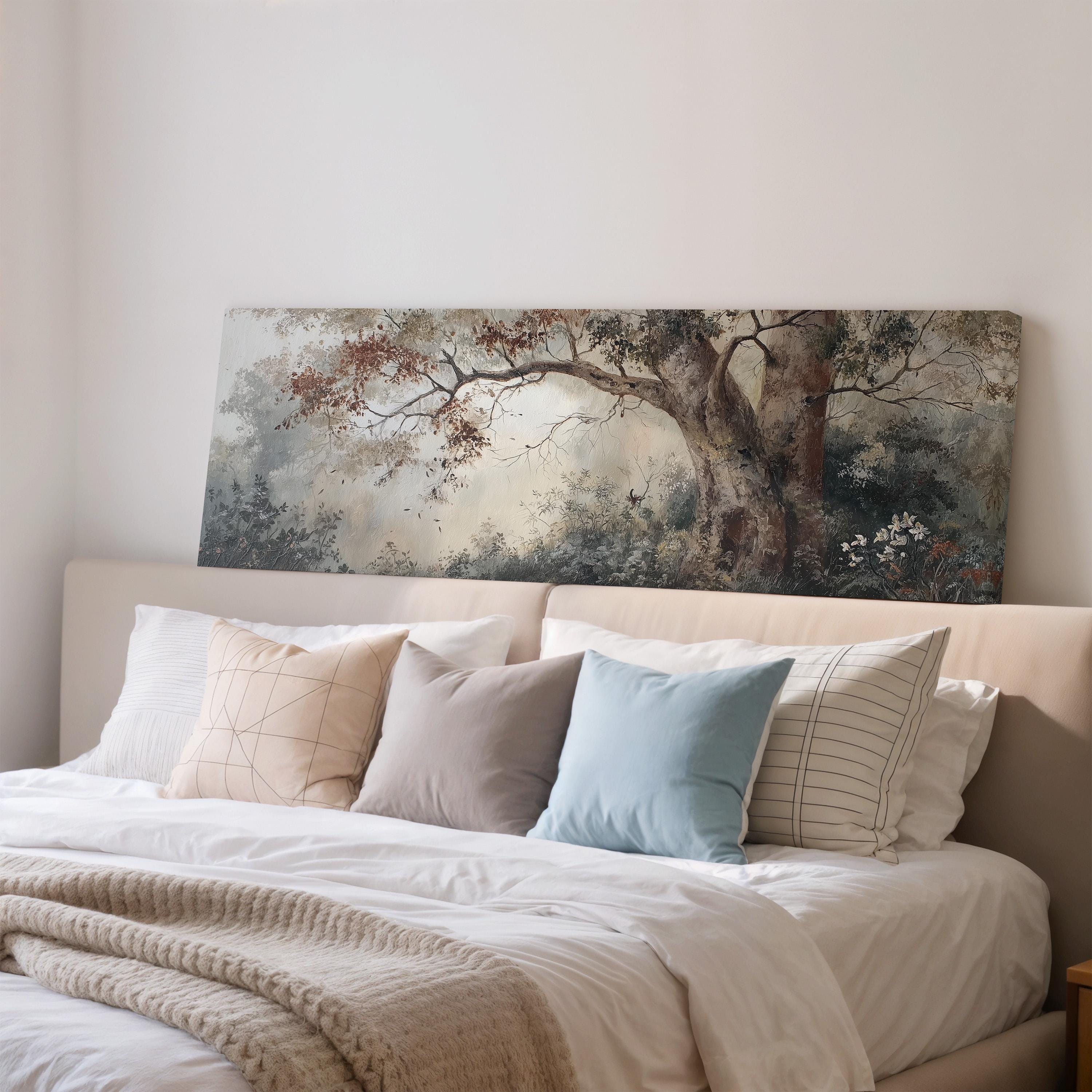 a large painting of a tree hanging above a bed with white bedding and various pillows.