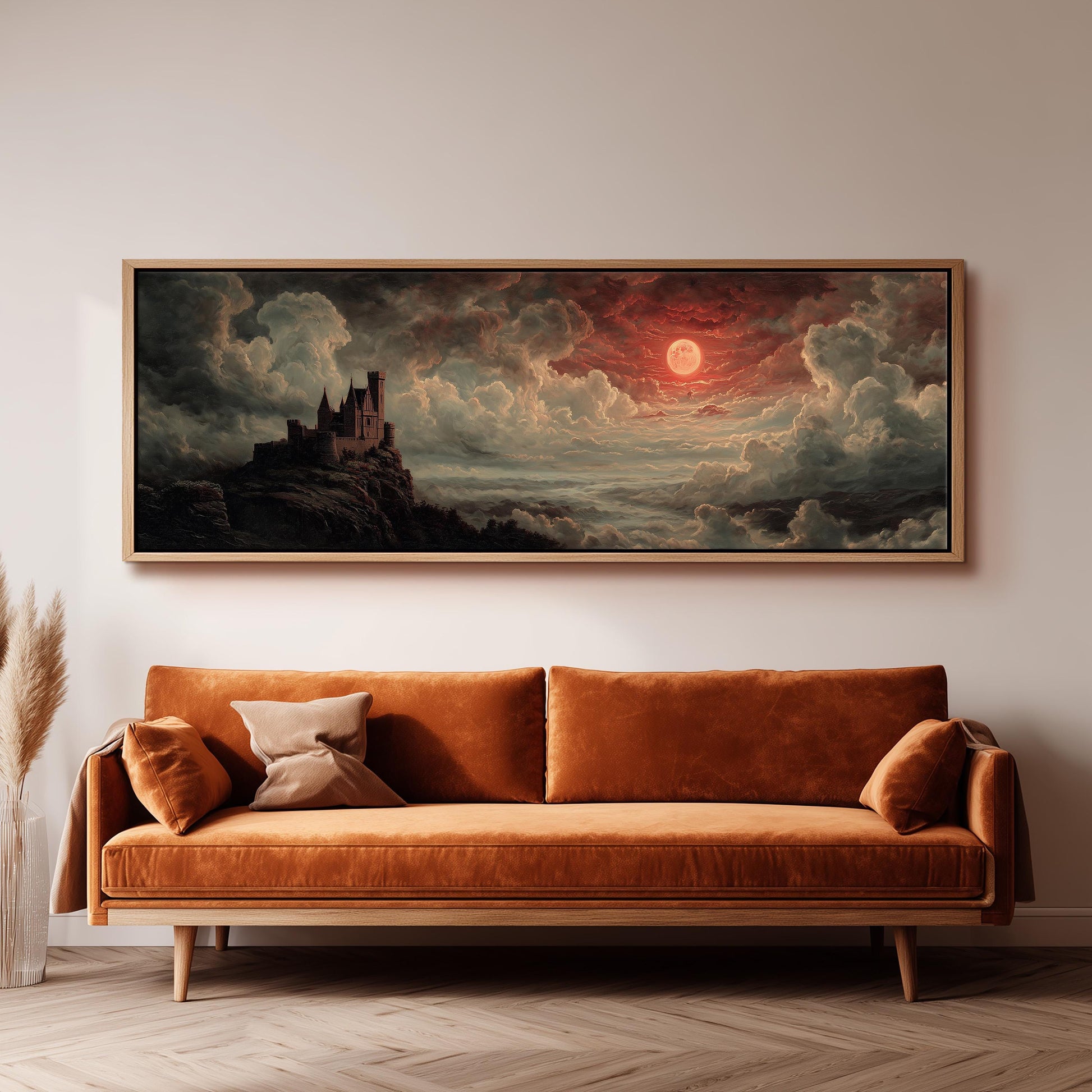 a large, framed painting of a castle on a cliff, with a dramatic sky and a red moon in the background. The painting is hanging on a wall above a brown sofa, creating a cozy and artistic atmosphere in the room.