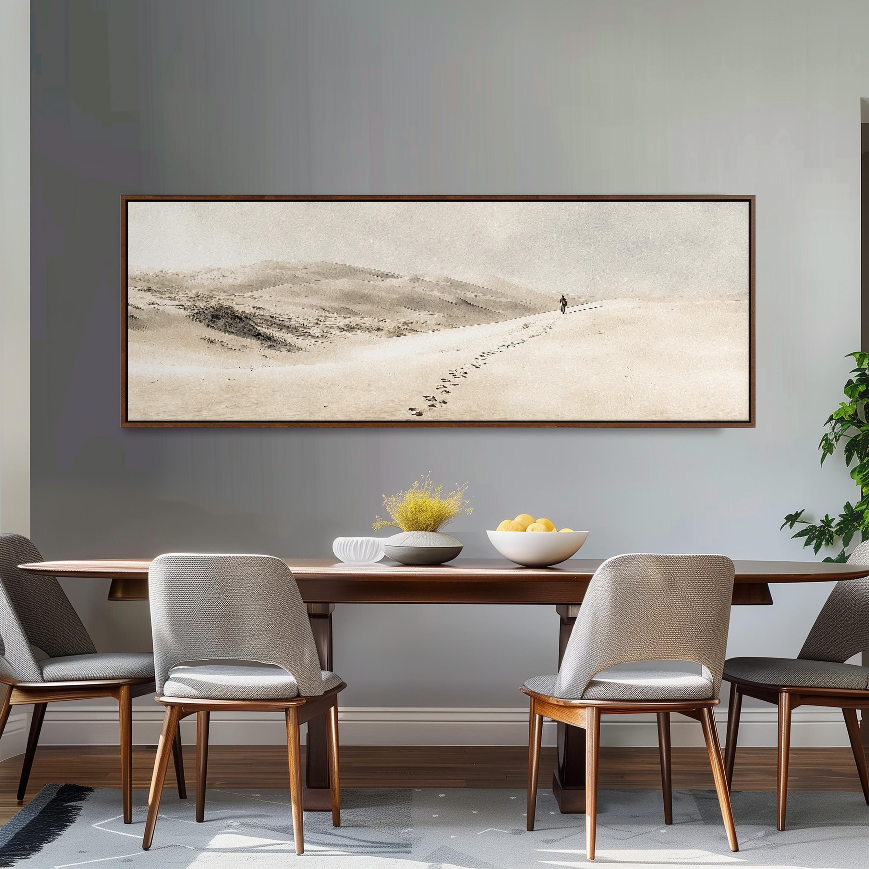 a dining room with a large framed landscape painting hanging on the wall above a wooden dining table with four chairs. The painting depicts a desert scene with a lone figure walking through the sand.