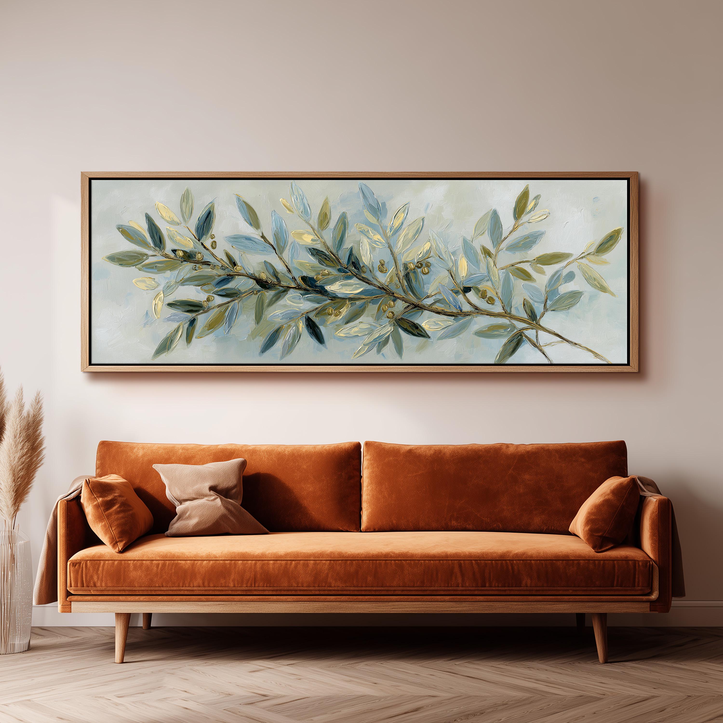a large painting of a branch with green leaves hanging on a wall above a brown sofa.