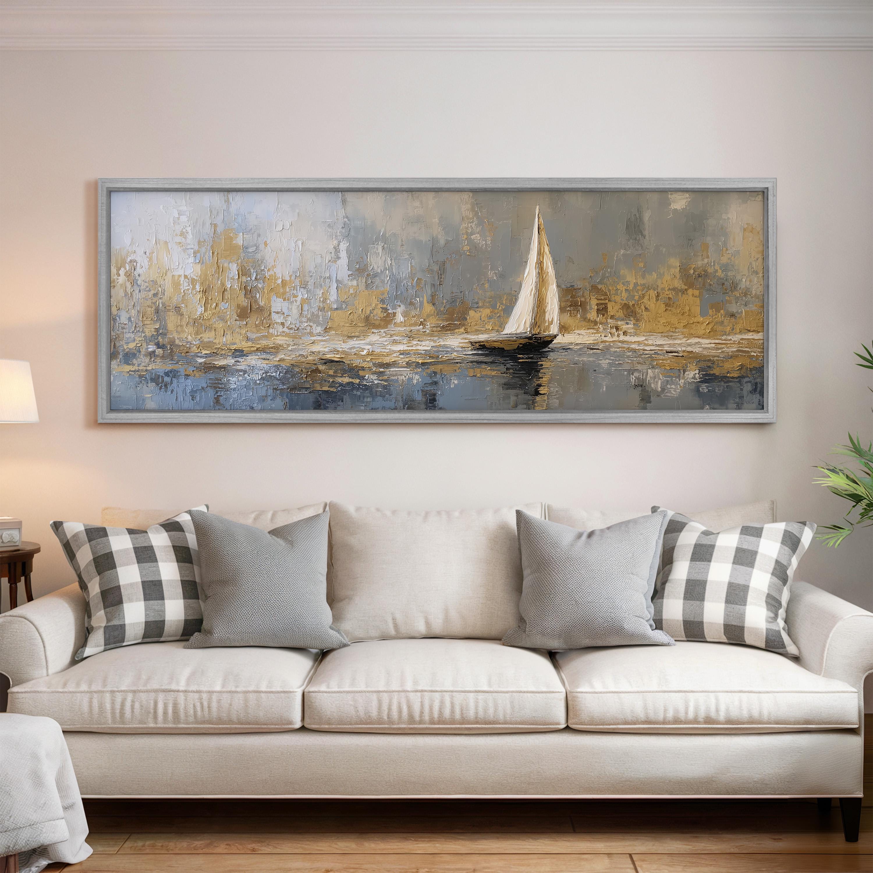 a large painting of a sailboat on a body of water, hanging on a wall above a white sofa with gray and white patterned pillows.