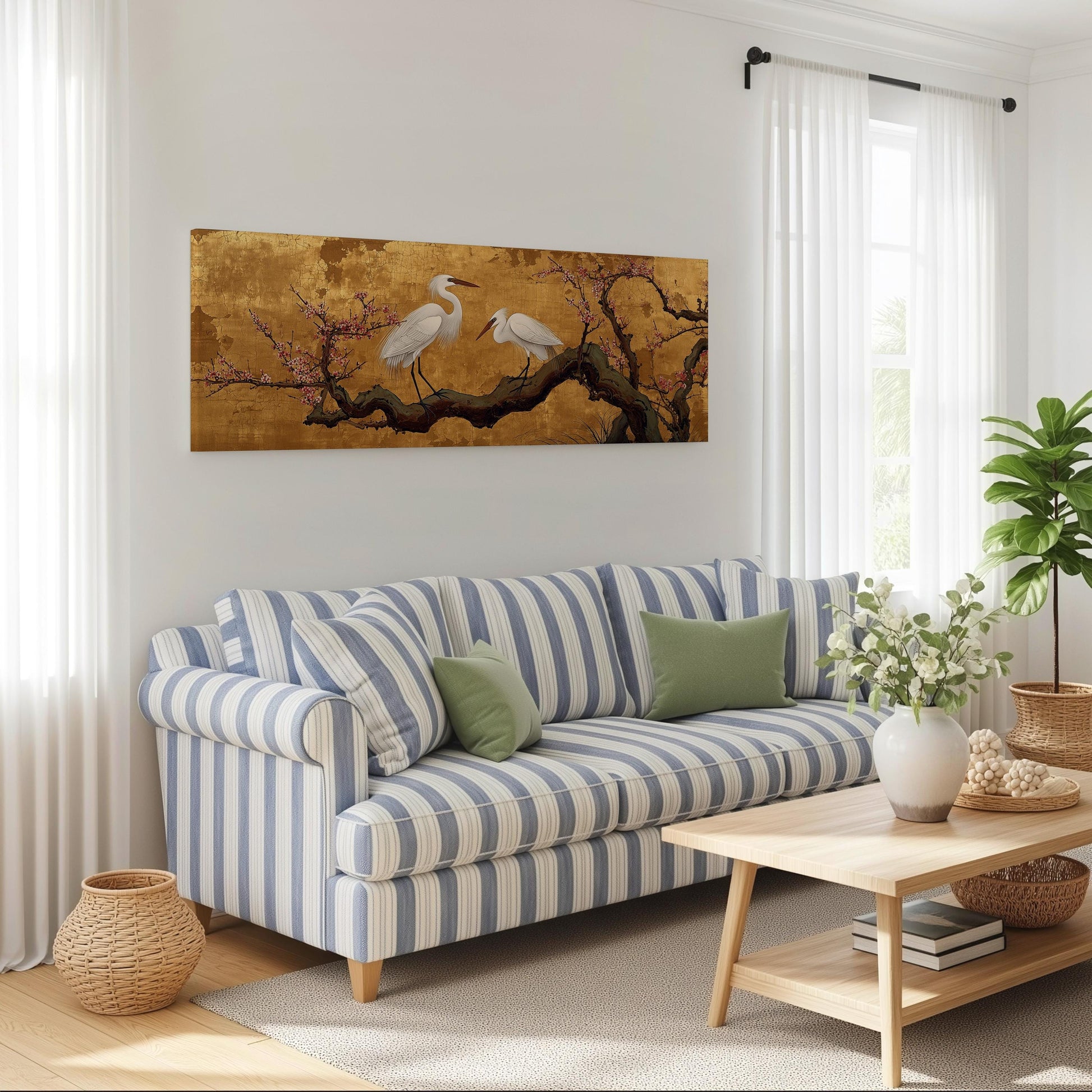 a cozy living room with a striped blue and white sofa, a wooden coffee table, and a large painting of two white birds perched on a branch with pink flowers.