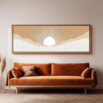 a large, rectangular, framed artwork depicting a sun-like design on a wall above a brown sofa with two pillows.