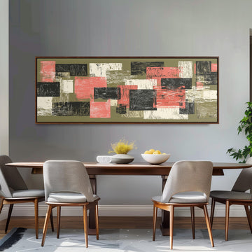 a dining room with a wooden table and four chairs. Above the table, there is a large abstract painting with a mix of pink, green, and black colors. The painting is hanging on a gray wall, and the dining table is set with a bowl of fruit and a vase of flowers.
