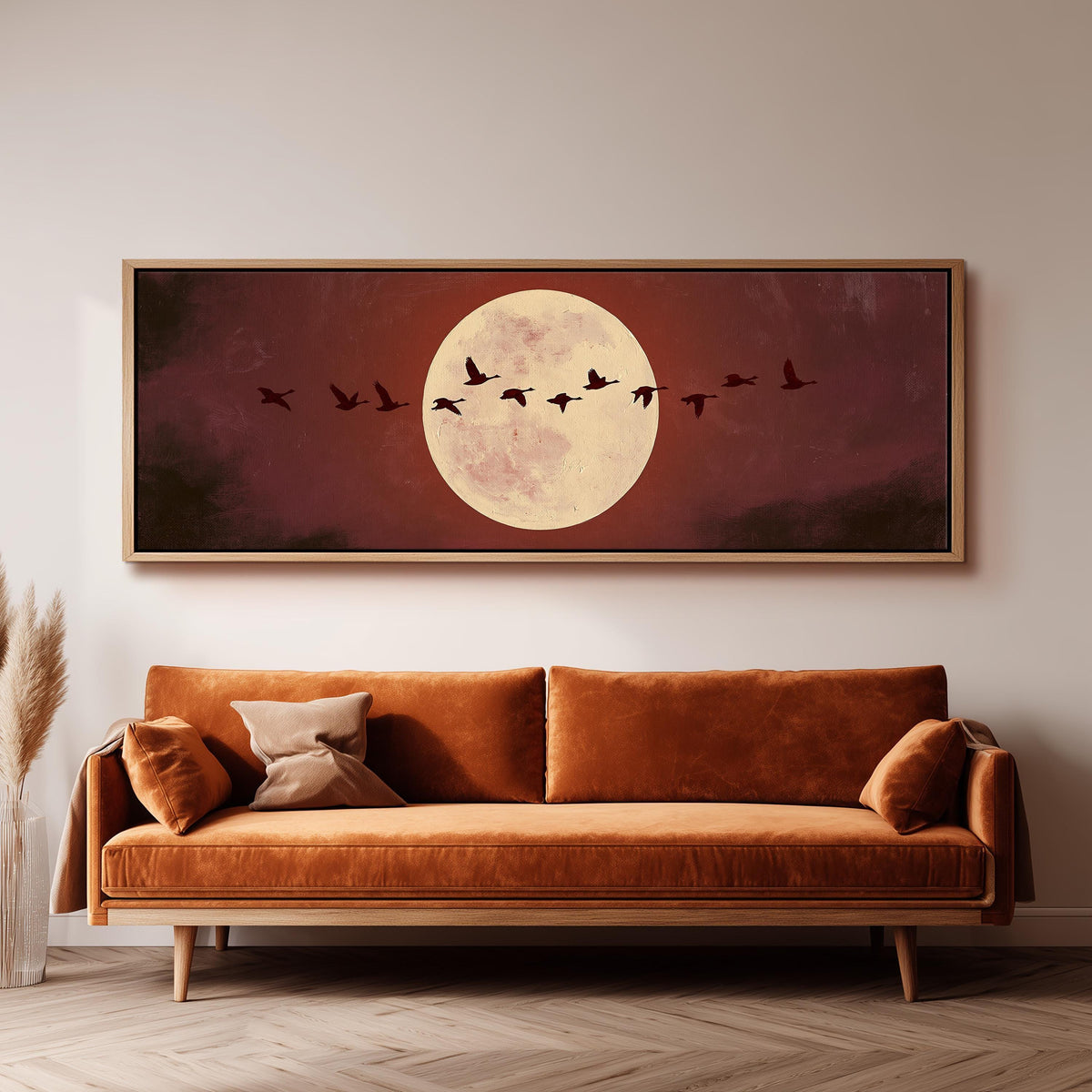 Geese crossing a pale moon on maroon panoramic canvas print above a sofa in a living room