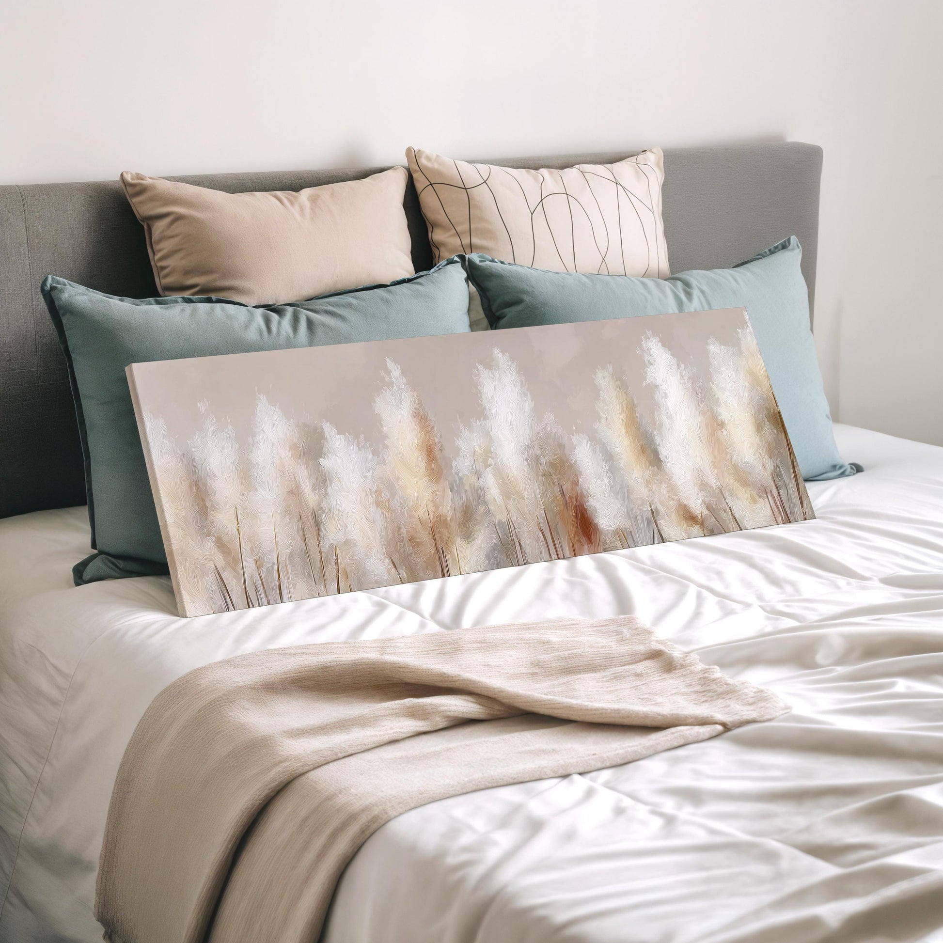a bedroom with a bed covered in white sheets and a painting of trees on the bed. The painting is placed on a white blanket, and there are several pillows surrounding it.