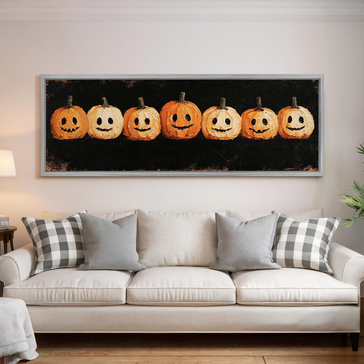 Row of smiling jack-o'-lanterns panoramic canvas print above a white sofa in a bright living room