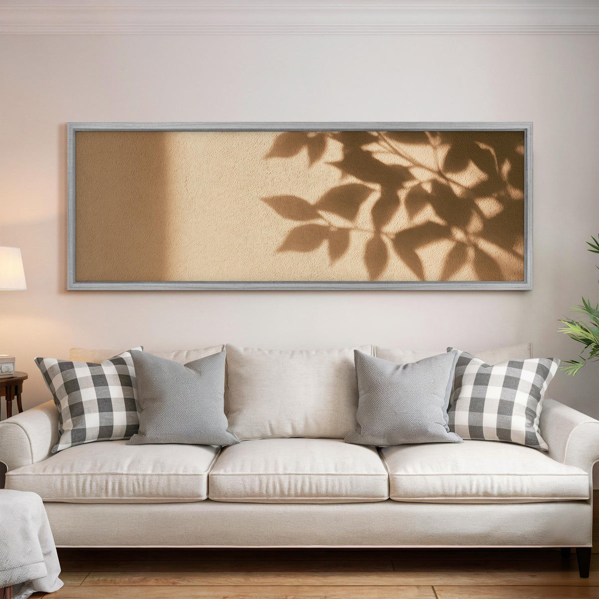 Leaf shadows on a golden plaster wall panoramic canvas print above a white sofa in a bright living room