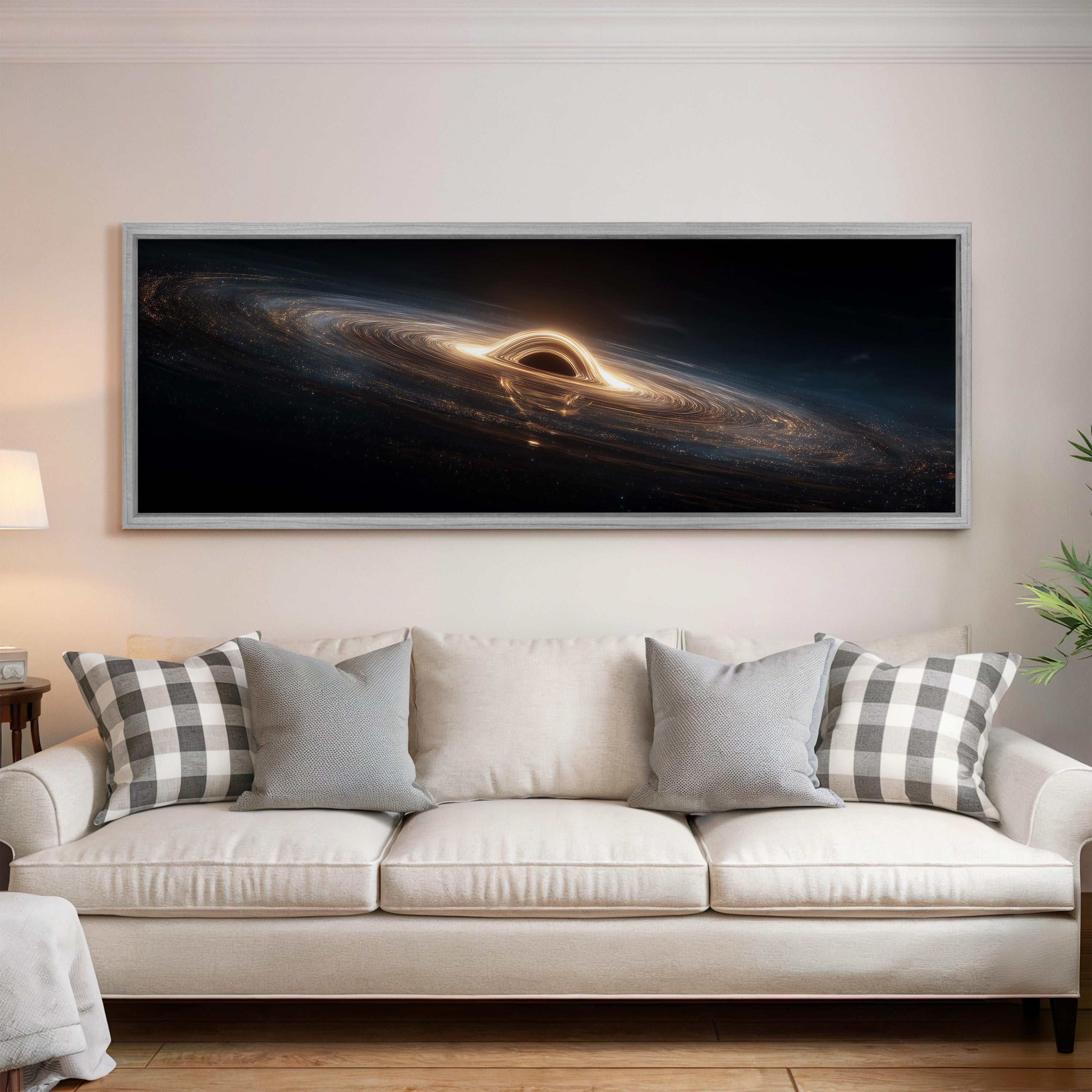 a large, framed artwork depicting a black hole in space, hanging above a white couch with patterned throw pillows.