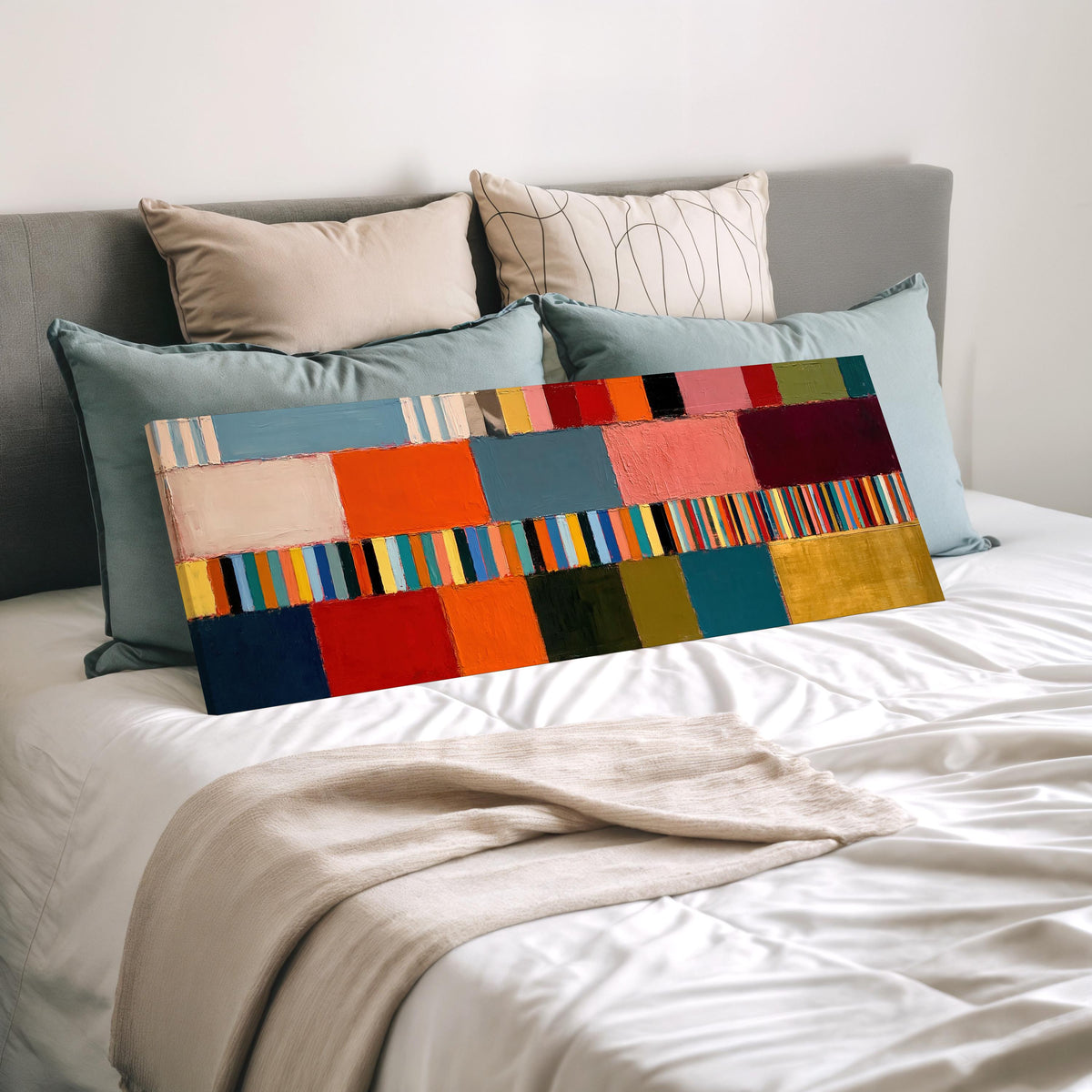 Rainbow patchwork color bands wide panoramic canvas print laid on a bed to show its size