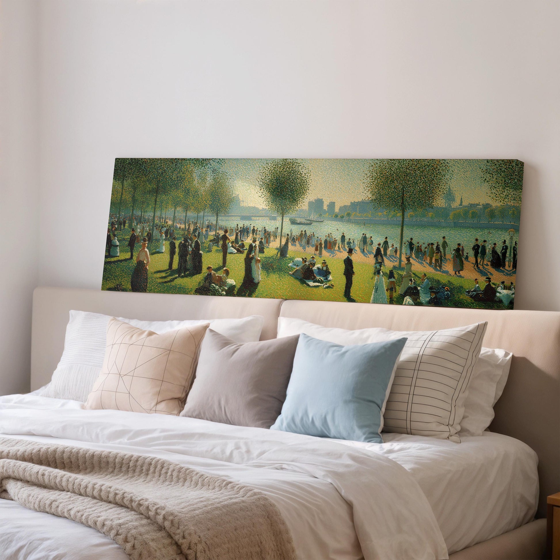 a large painting of a park scene with people enjoying the outdoors, displayed on a wall above a bed with pillows.