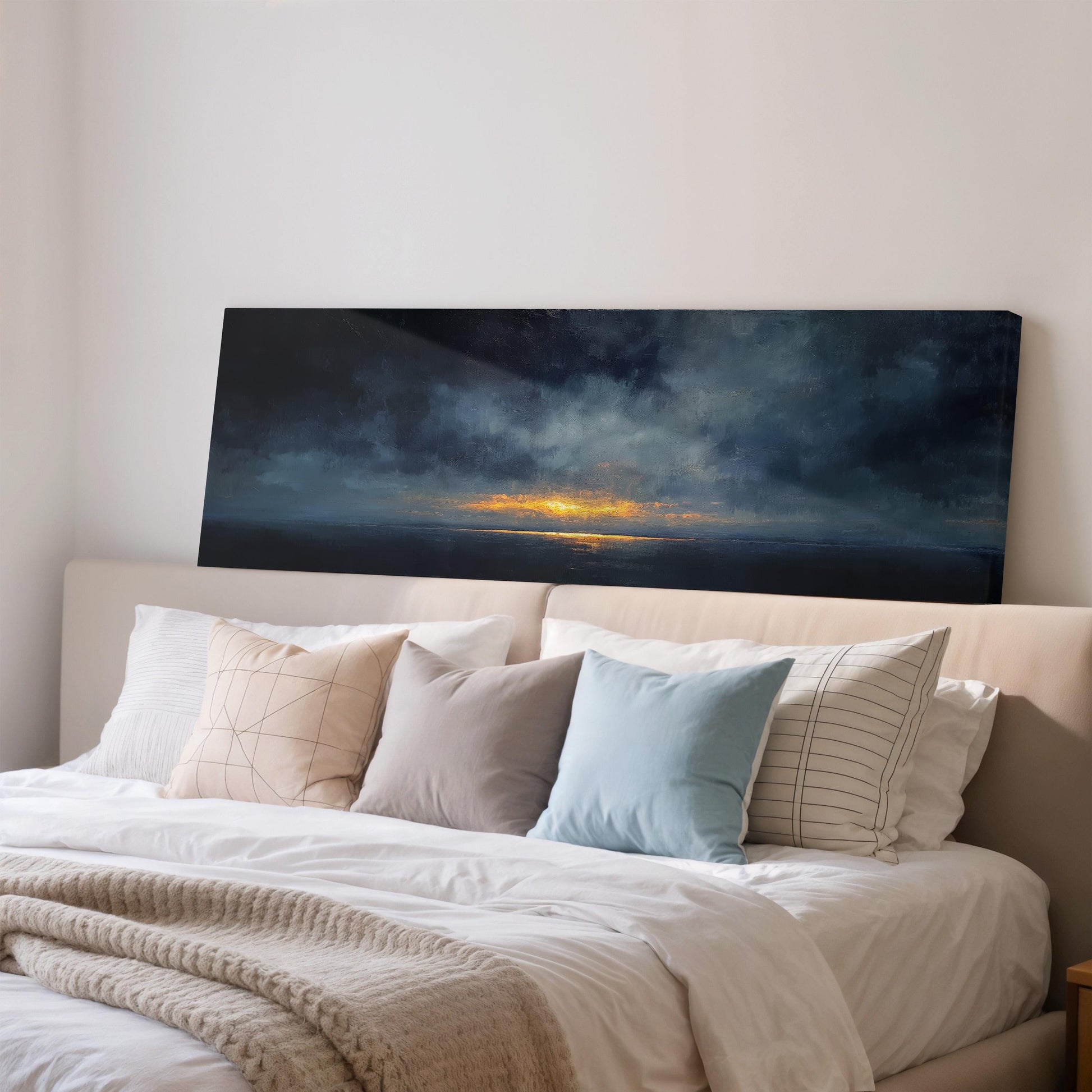 a bedroom with a large bed covered in white sheets and pillows. Above the bed, there is a large painting depicting a sunset over the ocean.