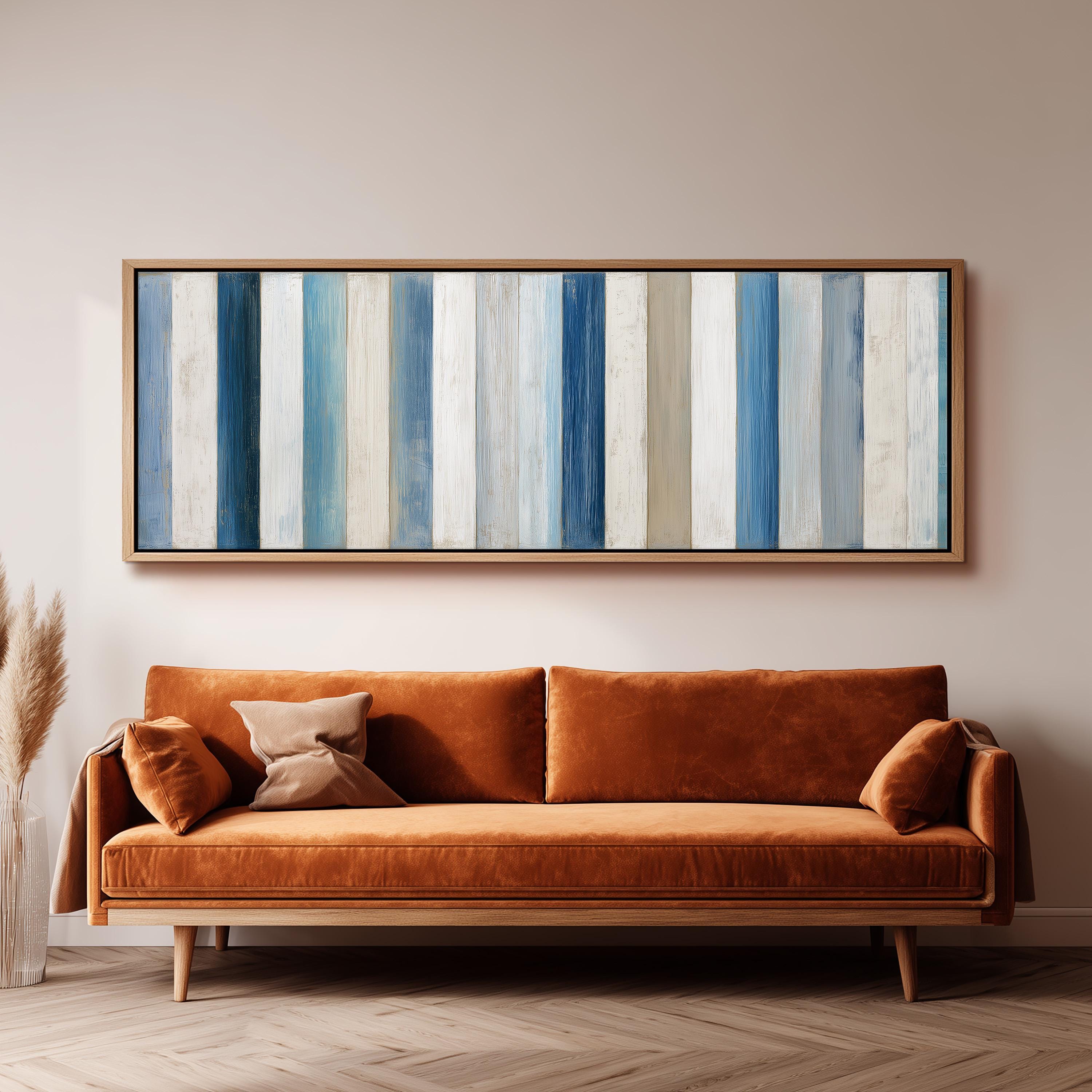 a cozy living room with a large orange sofa and a framed artwork of blue and white vertical stripes hanging on the wall above it.