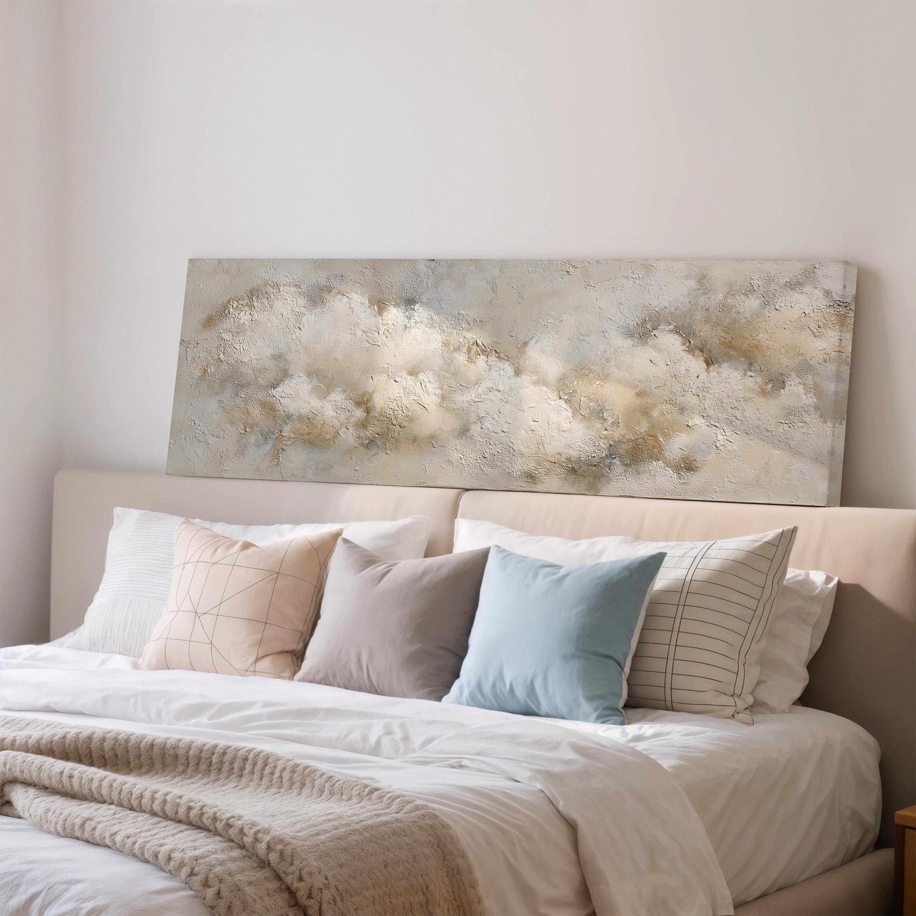 a cozy bedroom with a large bed adorned with white sheets and a blue pillow. Above the bed, there is a large painting depicting a cloudy sky.