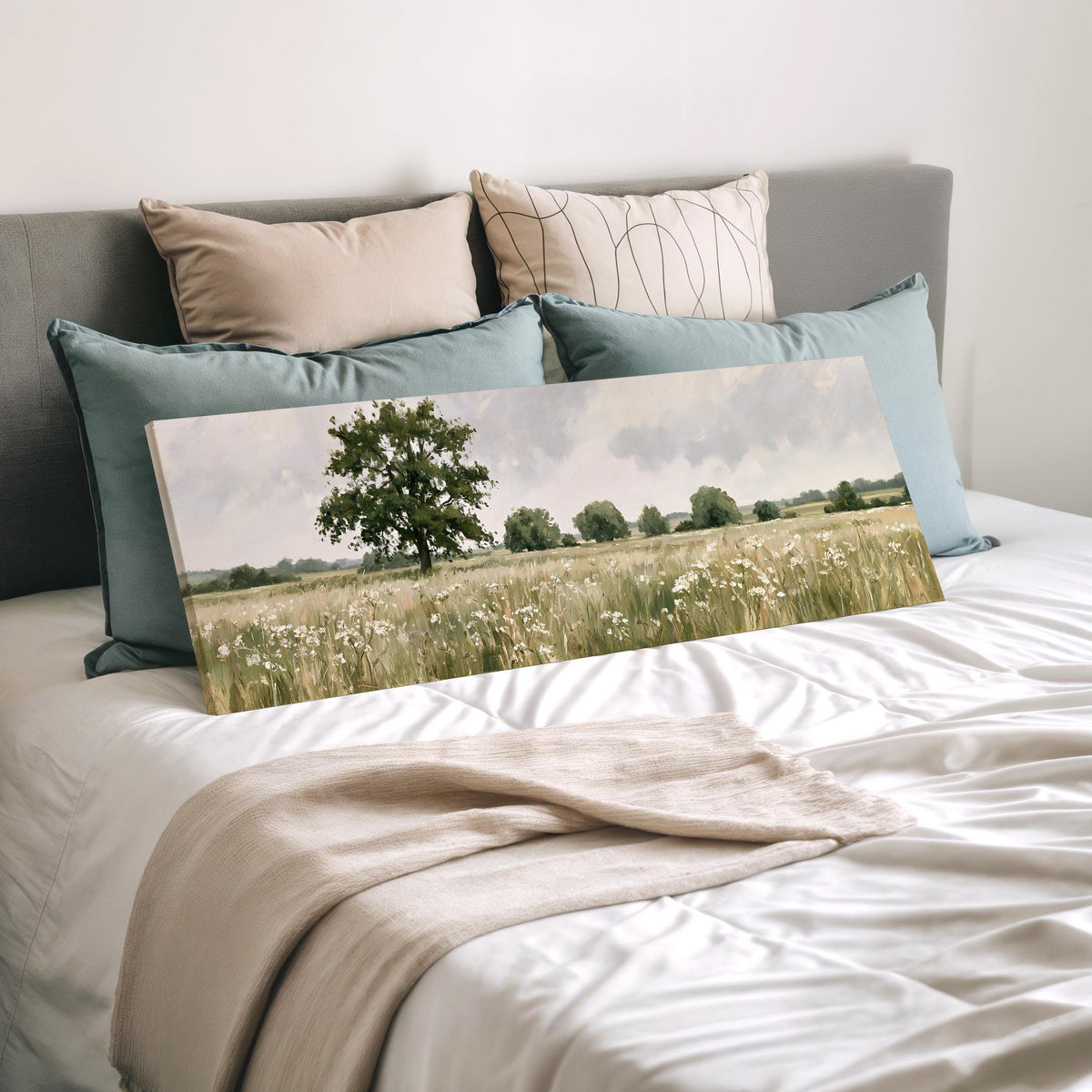 Lone oak tree in a daisy meadow wide panoramic canvas print laid on a bed to show its size